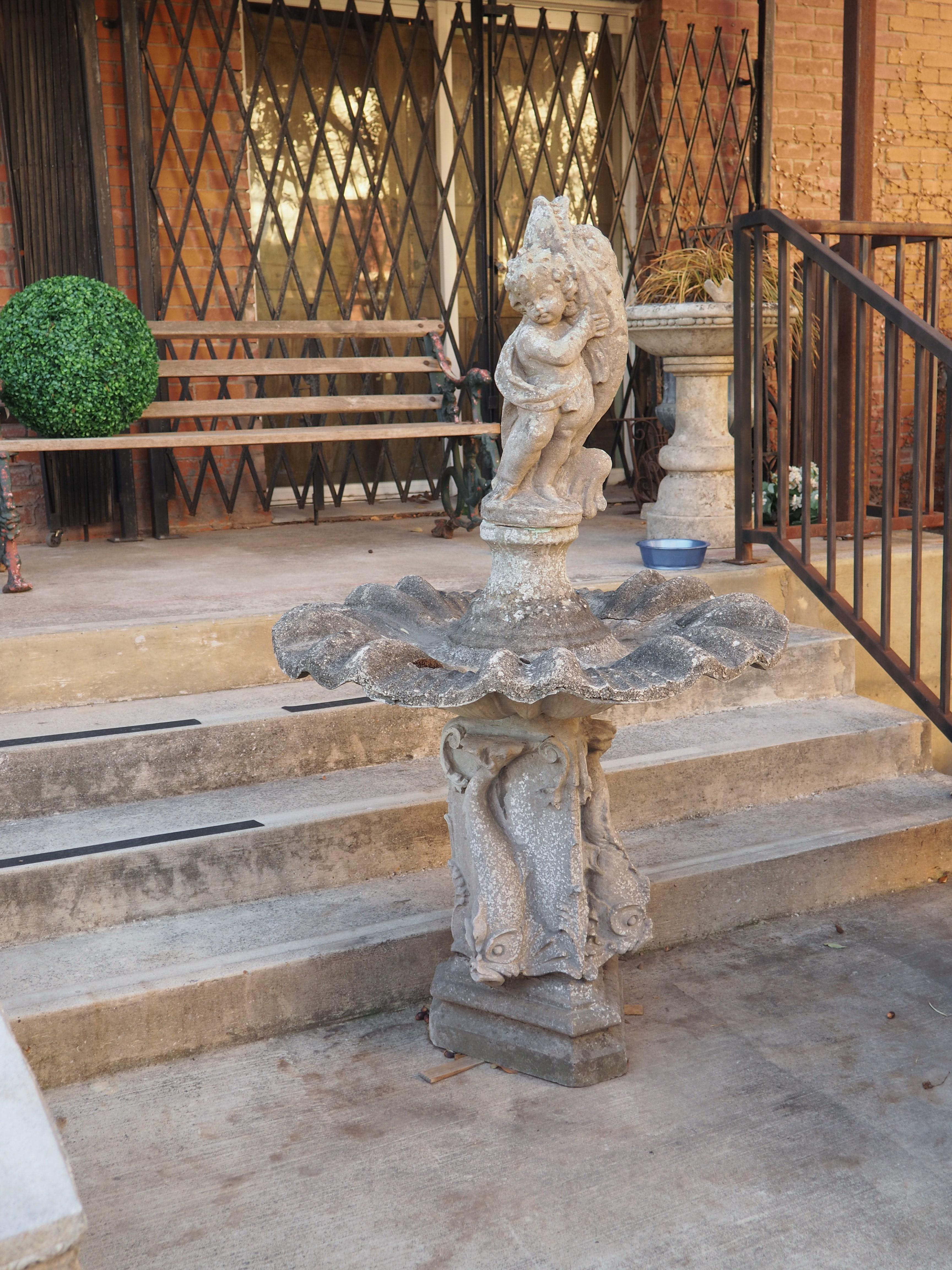 Made from reconstituted stone, or cast stone, which is a mixture of crushed stone and cement, this putto and dolphin center fountain element was cast in France, circa the 1950’s. Decades of exposure to the elements has resulted in a sought-after