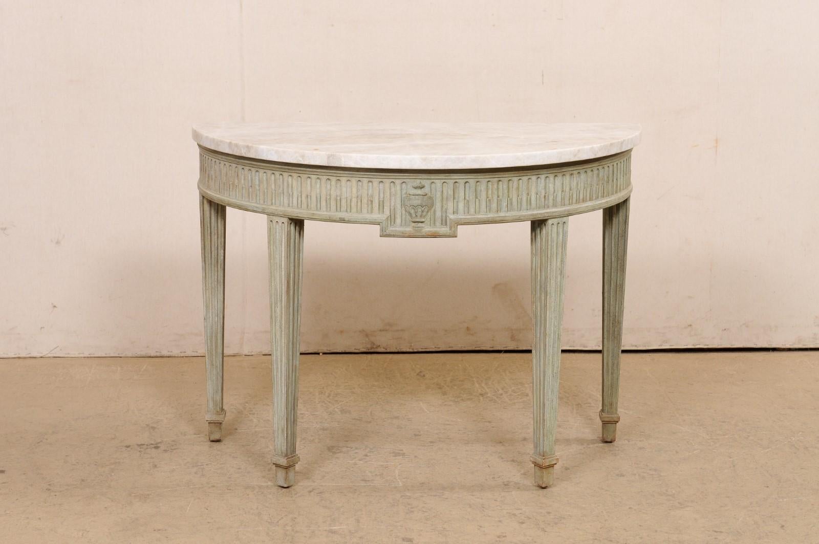 A French Neoclassical style carved and painted-wood demi-lune table with quartz top from the mid 20th century. This mid-century table from France has a half-moon shaped quartz top over a rounded apron, carved with fluting and an urn featured at