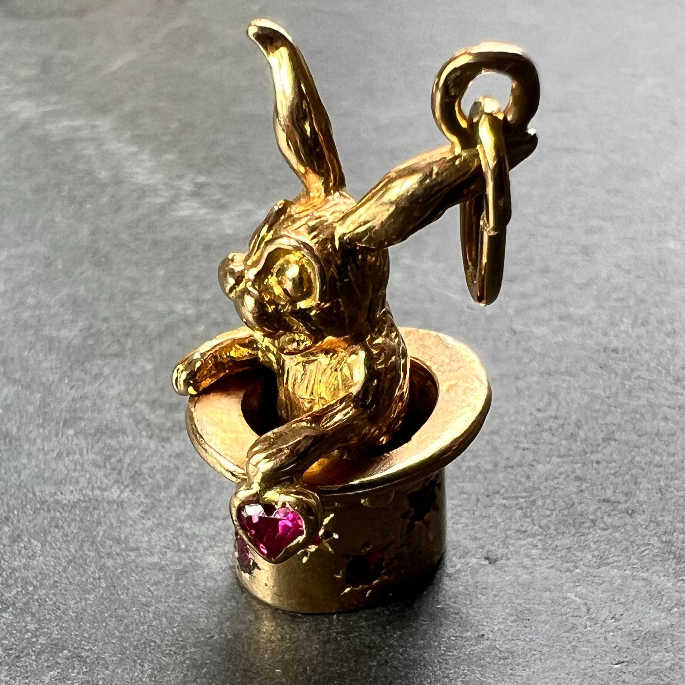 A French 18 karat (18K) yellow gold charm pendant designed as a magician’s top hat set with eight round rubies, containing a moving rabbit holding a ruby heart. Stamped with the eagle's head for 18 karat gold and French manufacture.

Dimensions: 2.4
