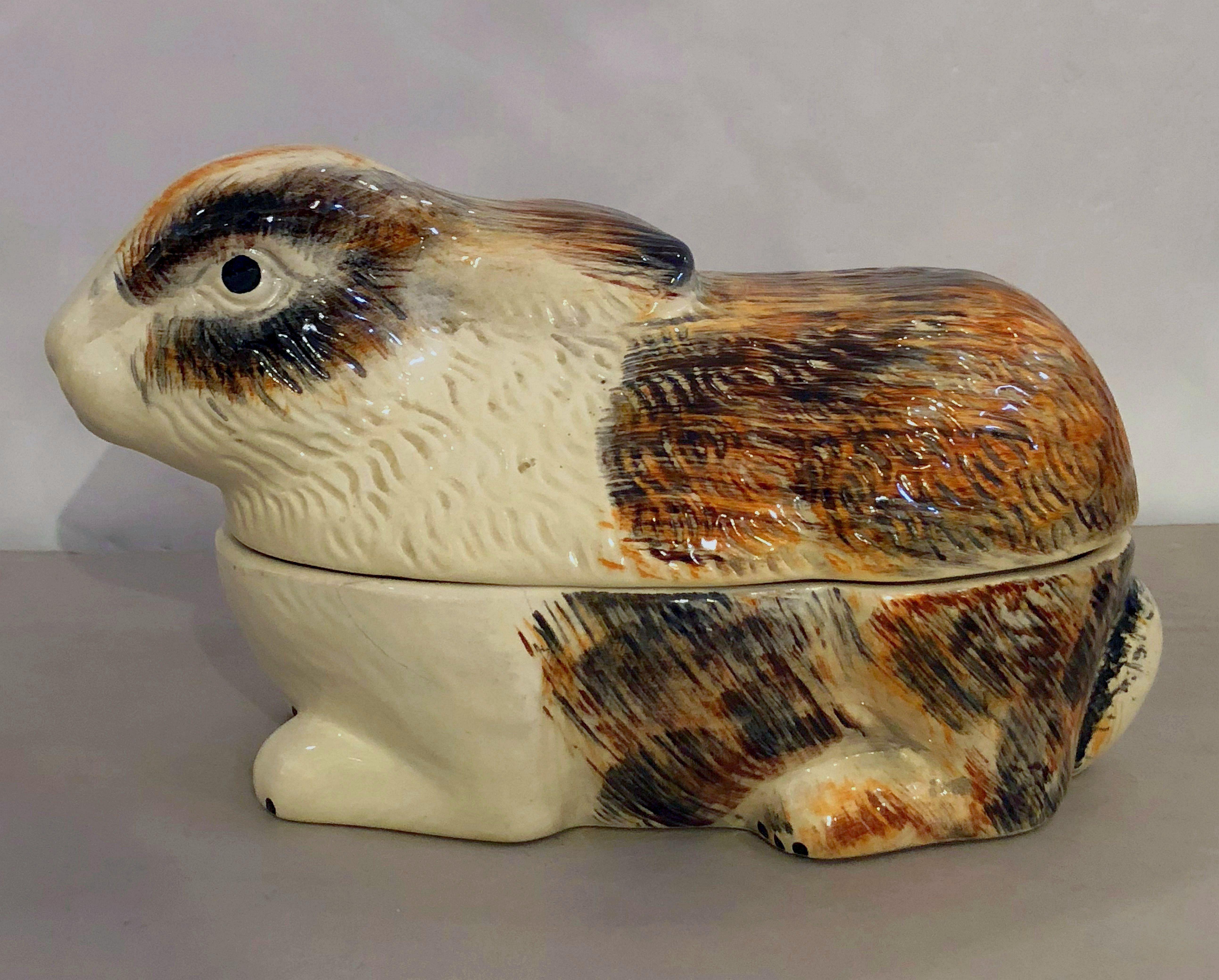 A fine French faience tureen (pâté terrine) with lid and under tray in the shape of a reclining rabbit by Michel Caugant.

Caugant signature on bottom.

