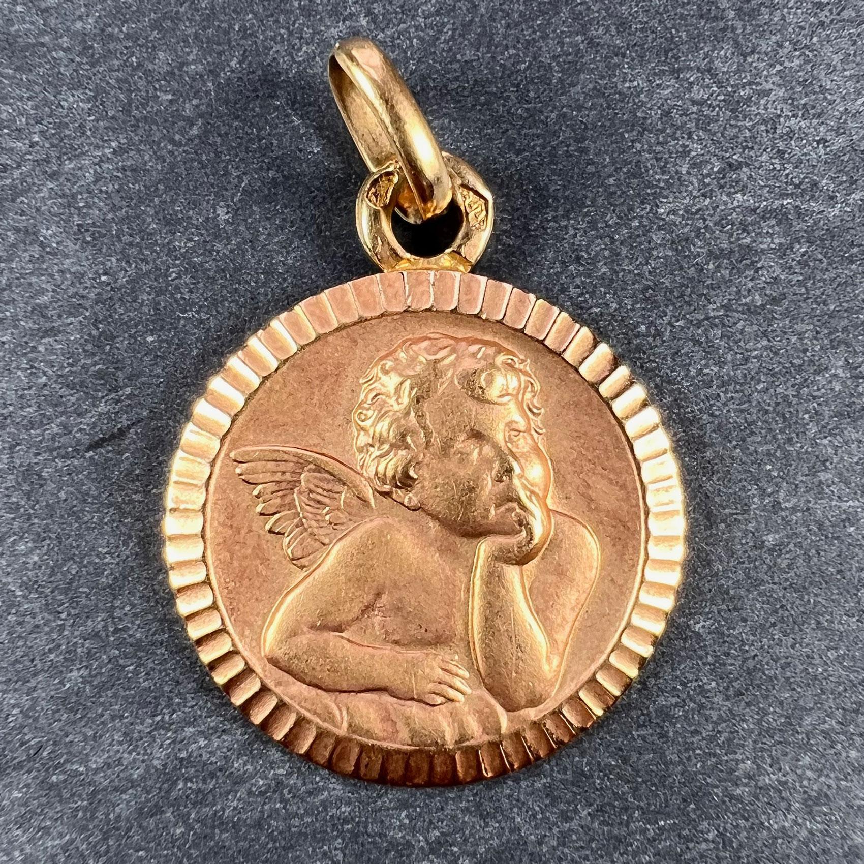Un pendentif de charme français en or rose 18 carats (18K) conçu comme une médaille représentant l'angelot de Rafael dans un cadre strié. Estampillée de la marque de l'aigle pour l'or 18 carats et de fabrication française avec une marque de