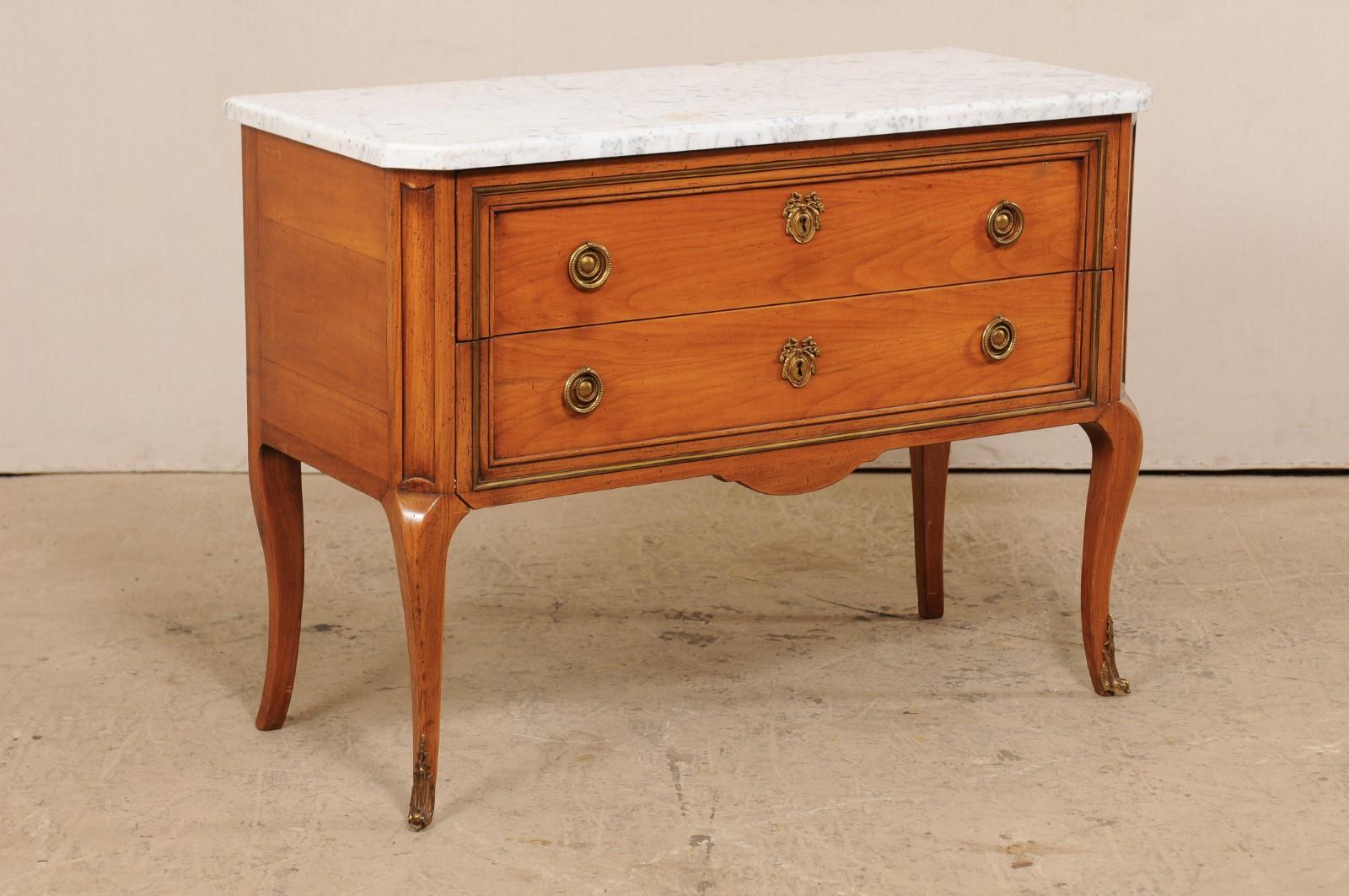 A French nicely raised chest with marble top. This vintage chest from France features a white marble top which rests atop a wooden chest consisting of two drawers flanking between canted front side posts, and raised elegantly upon four slender