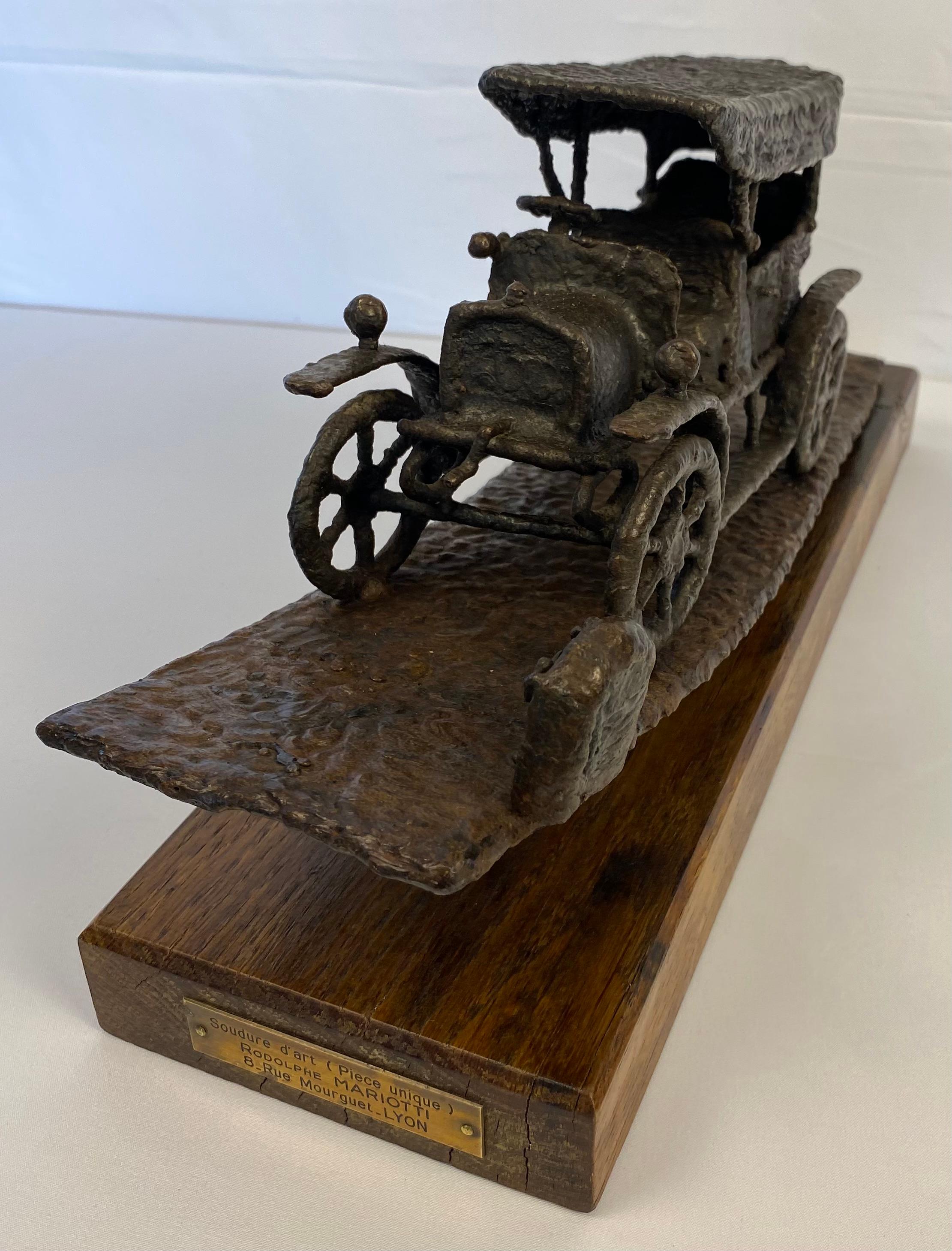 A fine quality and delightfully heavy sculpted iron motoring trophy car.
Automobile depicted is circa 1920s. 

Collectible and Commemorative of the ‘Rally U.C.O.L. Challenge - Driver Pierre Martel.  Signed by the Creative Artist Rodolphe Mariotti,