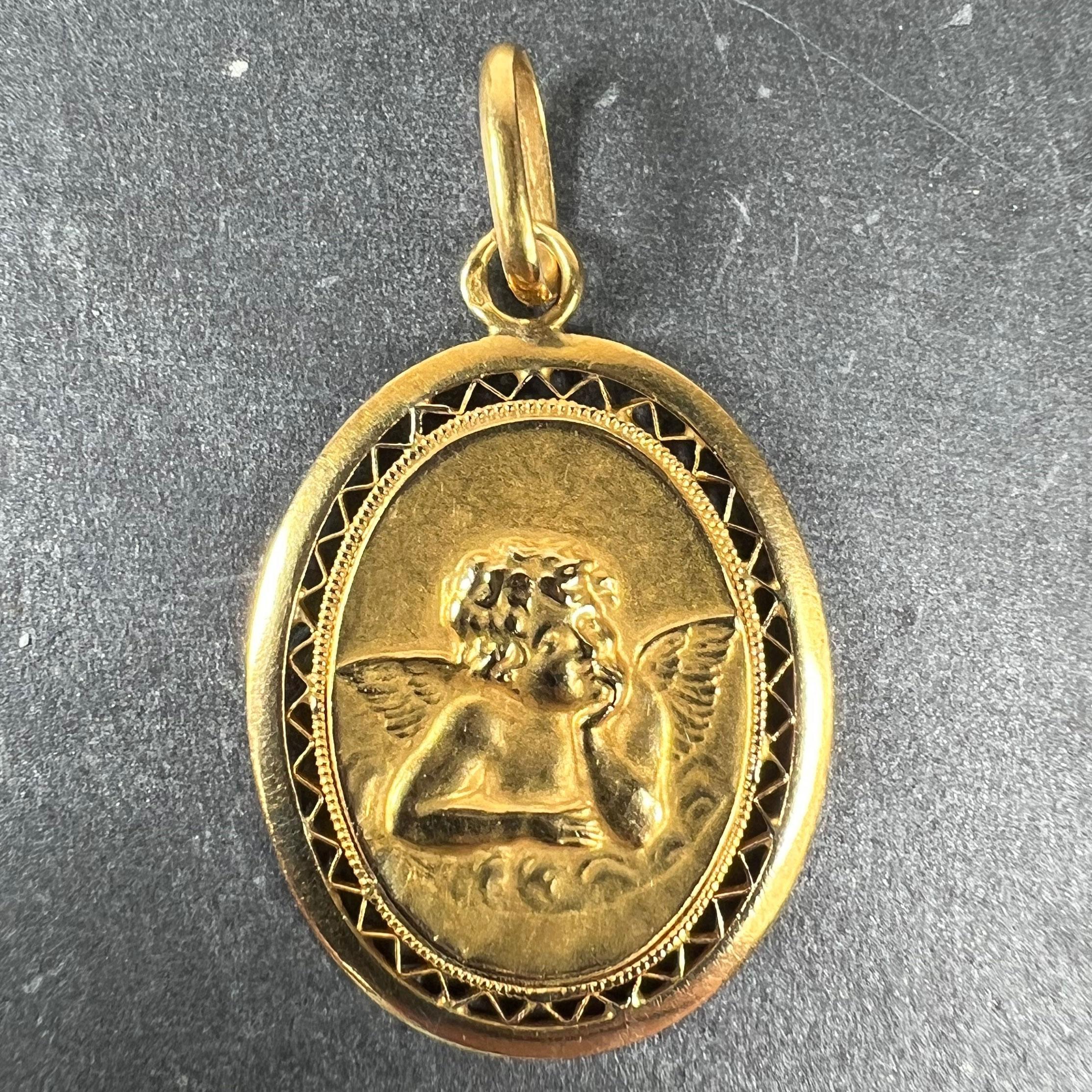 A French 18 karat (18K) yellow gold charm pendant designed as a oval medal depicting Raphael’s cherub with pierced zig-zag frame. Stamped with the eagle mark for 18 karat gold and French manufacture with an unknown maker's mark. 

Dimensions: 2.3 x