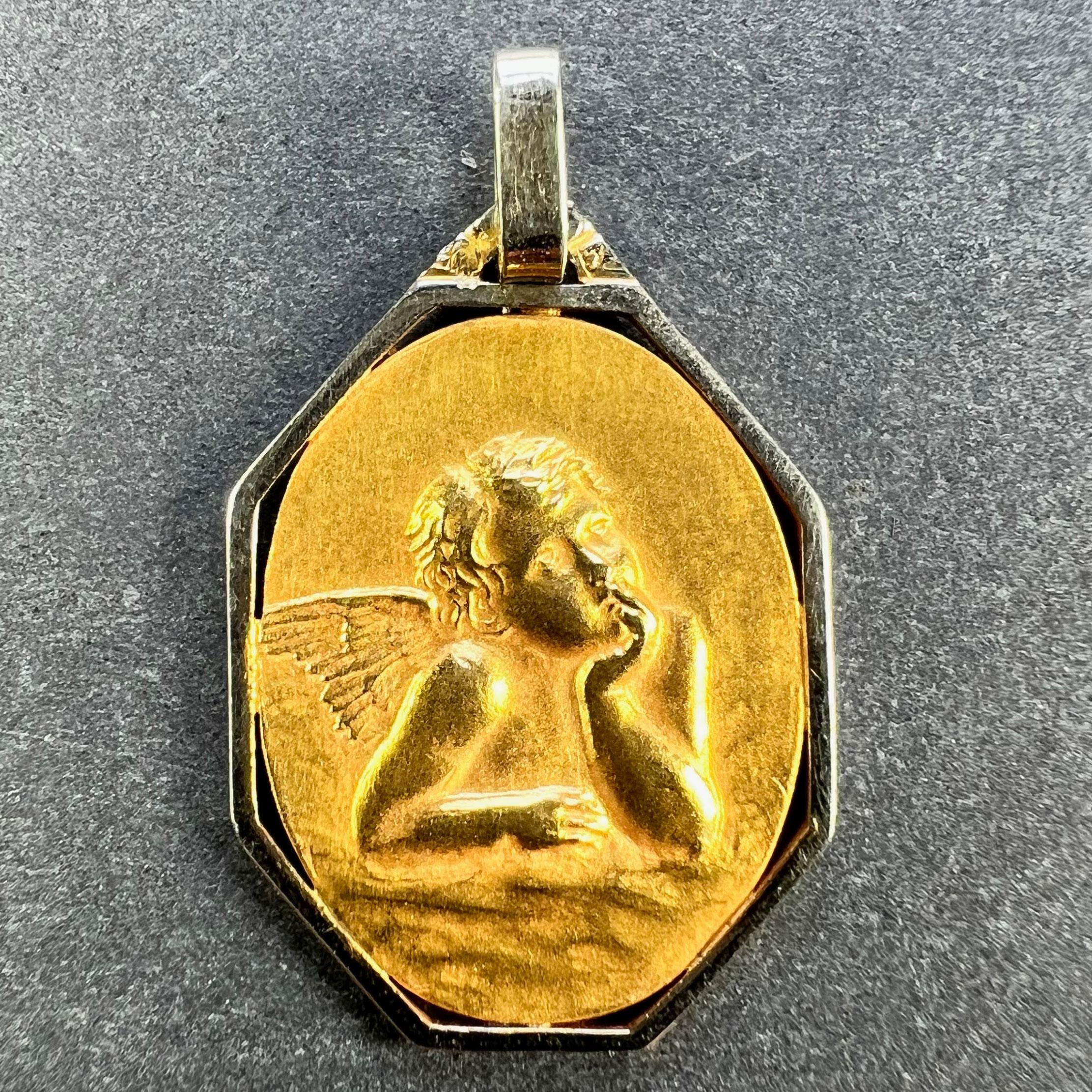A French 18 karat (18K) yellow gold charm pendant designed as an oval medal depicting Raphael’s cherub within an octagonal white gold frame. Stamped with the eagle mark for 18 karat gold and French manufacture with an unknown maker's mark. 