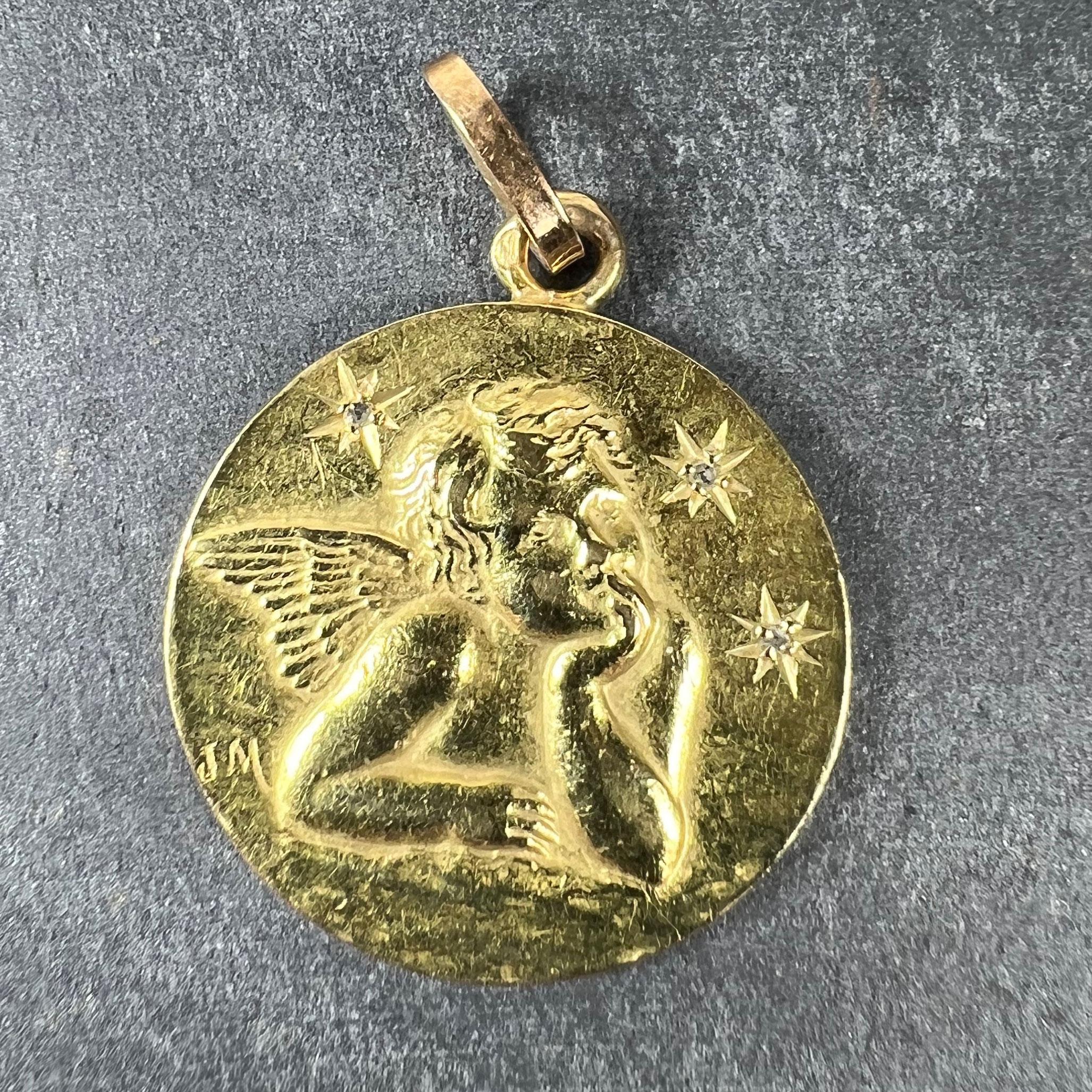 A French 18 karat (18K) yellow gold charm pendant designed as a round medal depicting Raphael’s cherub with three stars above set with rose-cut diamonds. The reverse with five bells. Signed JM. Stamped with the eagle mark for 18 karat gold and