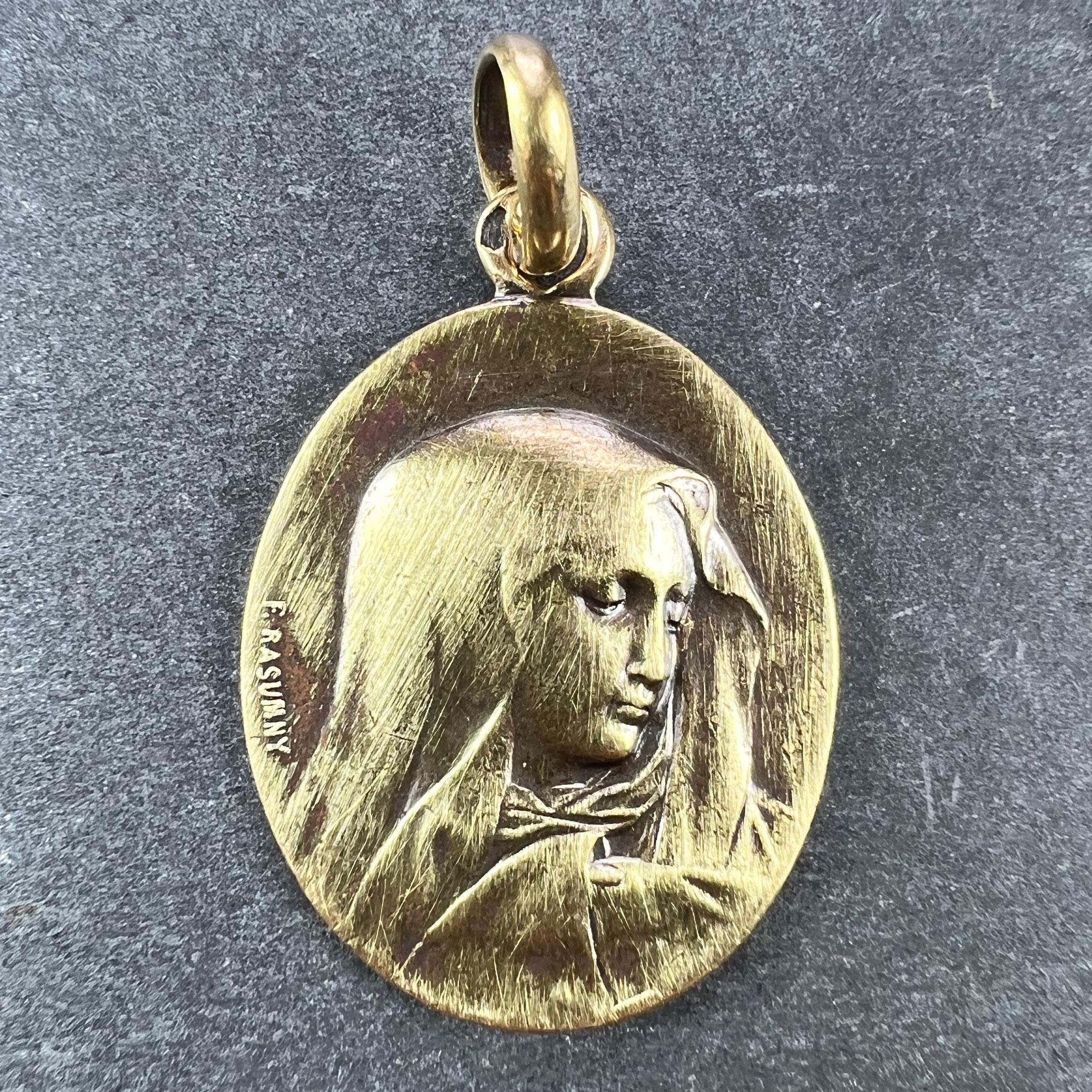 An 18 karat (18K) yellow gold oval charm pendant designed as a medal depicting the Virgin Mary. Signed F. Rasumny. Engraved to the reverse 'Charles' with the date 1st Decembre 1917. Stamped with the eagle’s head for French manufacture and 18 karat