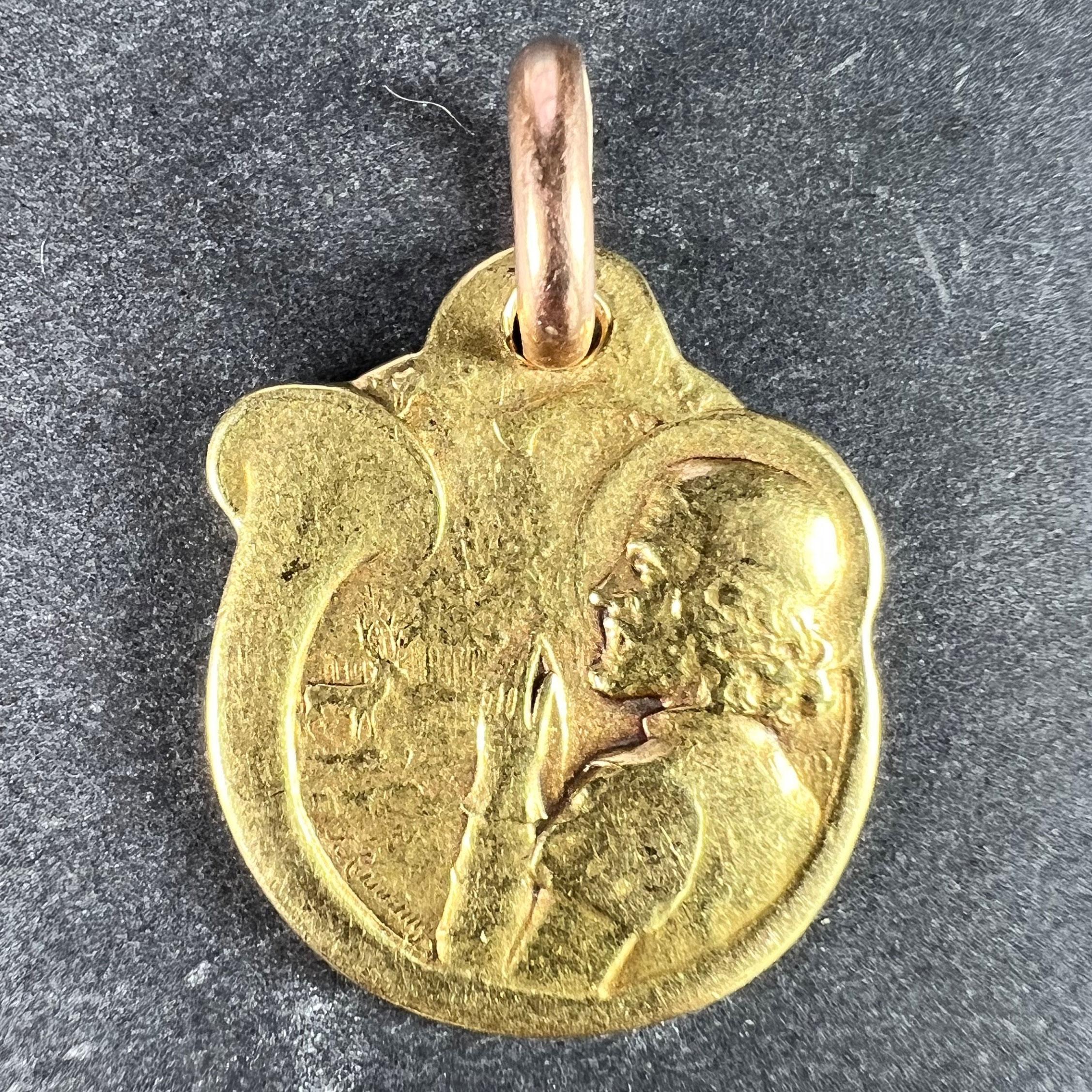 A French 18 karat (18K) yellow gold charm pendant designed as an engraved medal depicting a praying man on a deer hunt surrounded by a hunting horn looking at a stag or deer in front of a forest. The reverse showing a stag head with sword and arrow