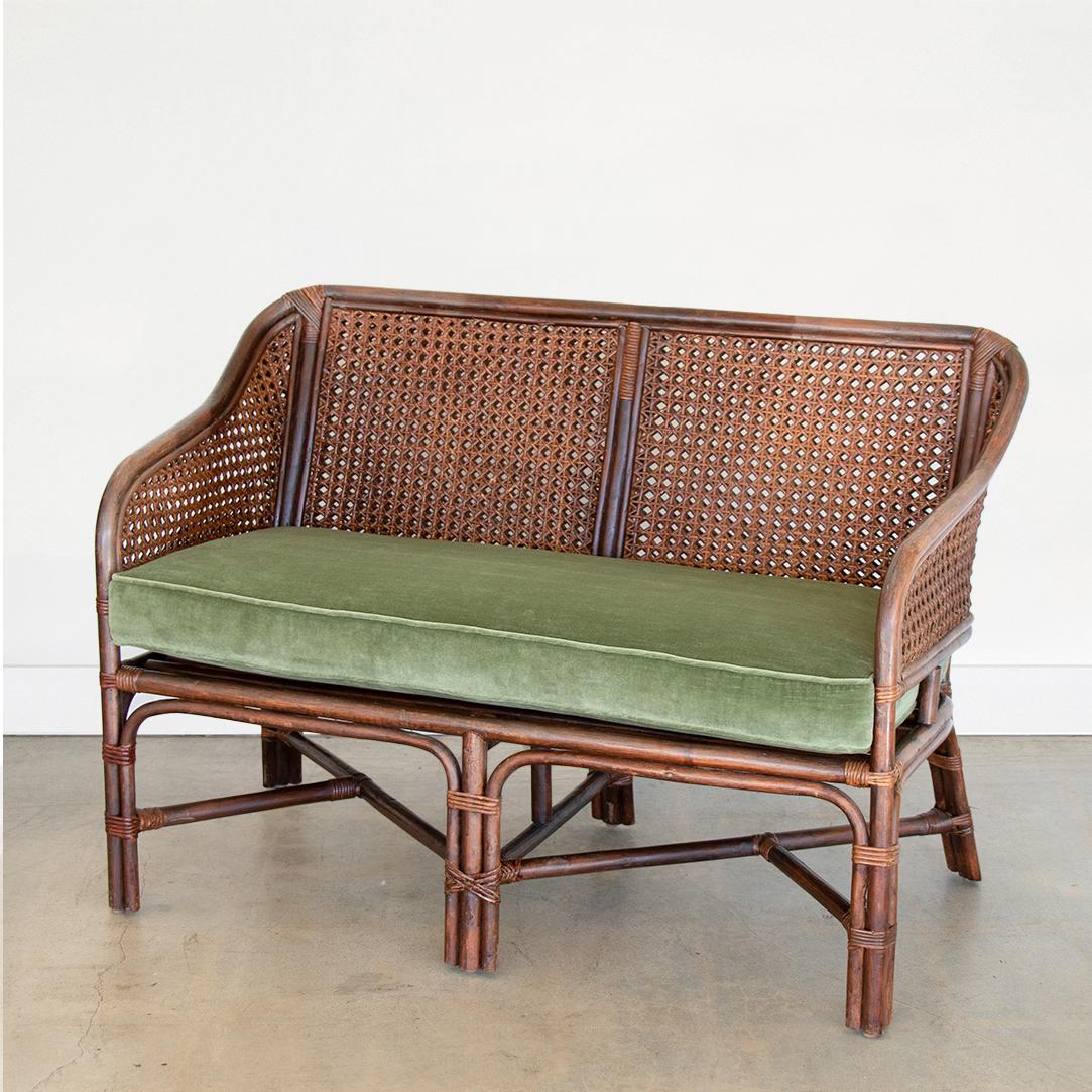 Beautiful rattan and cane settee from France. Original dark stain on rattan frame and cane back. Wrapped rattan detailing at joints and nice curved lines on arms. Newly upholstered seat cushion in green velvet. Nice vintage condition with great age