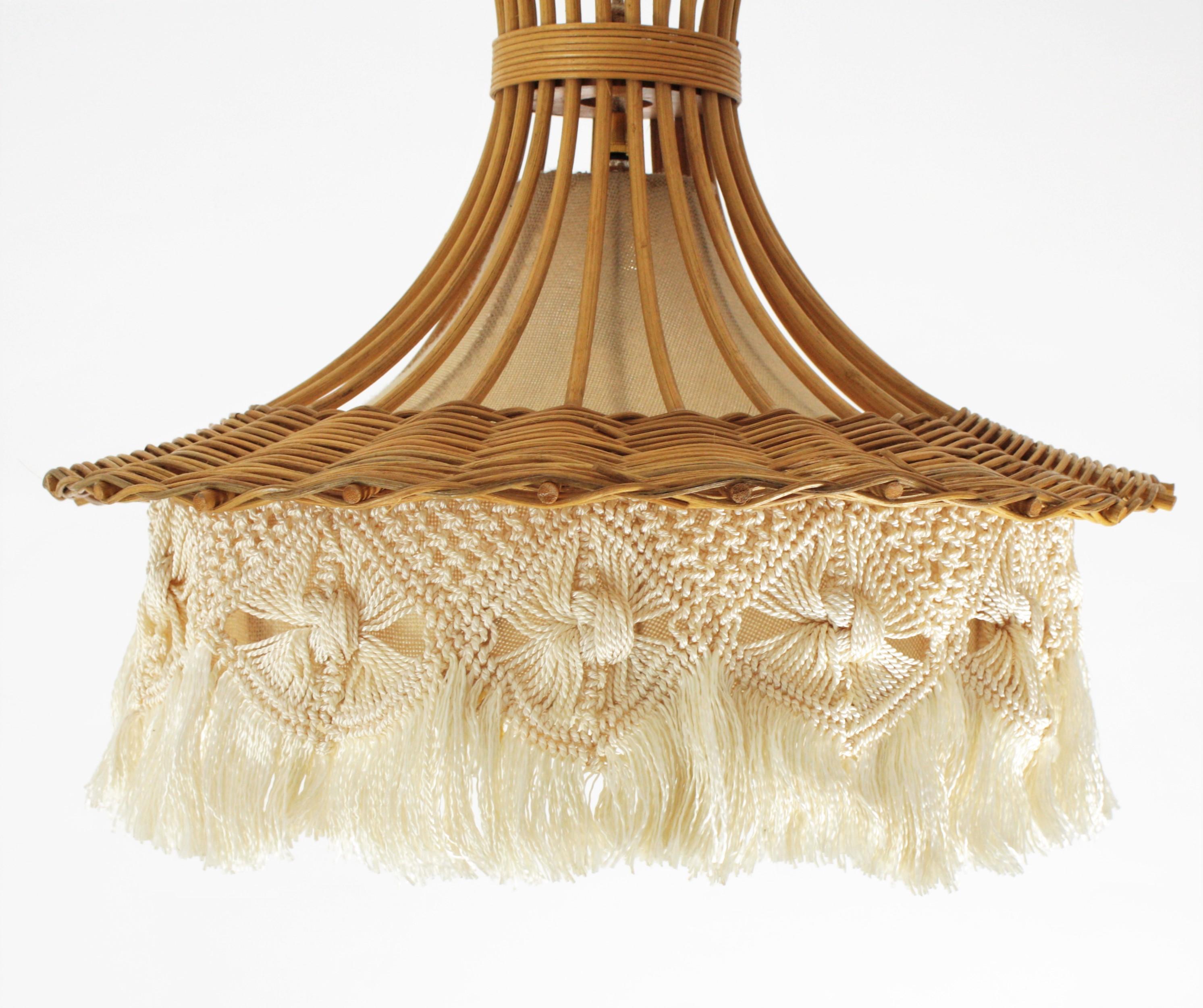 Stylish handcrafted rattan and wicker pagoda shaped chandelier with macrame and fringed bottom. France, 1960s-1970s.
This beautiful pendant features a pagoda shaped shade handcrafted with rattan canes joined between them with wicker canes. It has