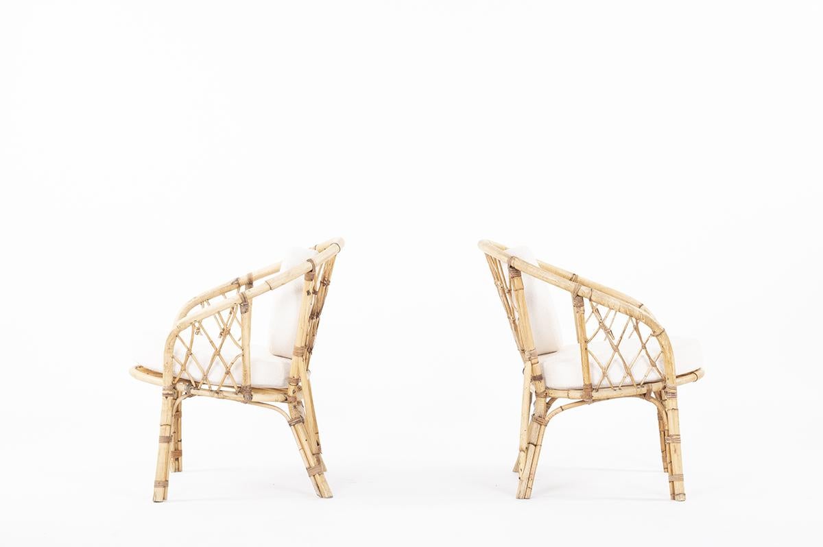 Pair of rattan armchairs made in 1950s, circle seat and back cushions made to measure in beige boucle fabric. 
This set coming from an orange grove of an house in the south of France.