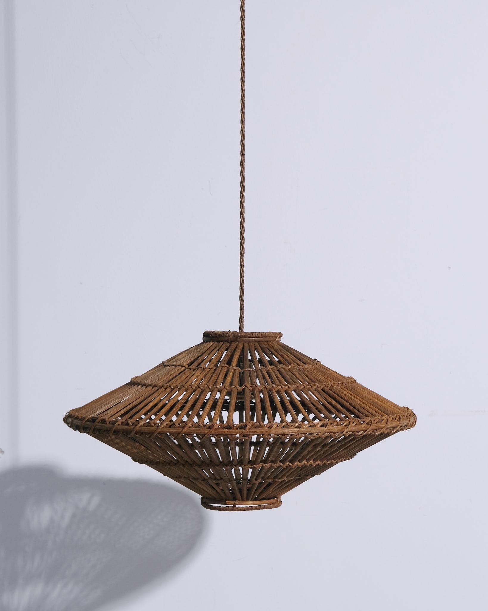 Un affascinante pendente da soffitto in rattan francese, risalente agli anni '60. Caratterizzato da un paralume in rattan intrecciato a mano con una tonalità calda e naturale, questo pezzo cattura l'eleganza rilassata del design francese di metà