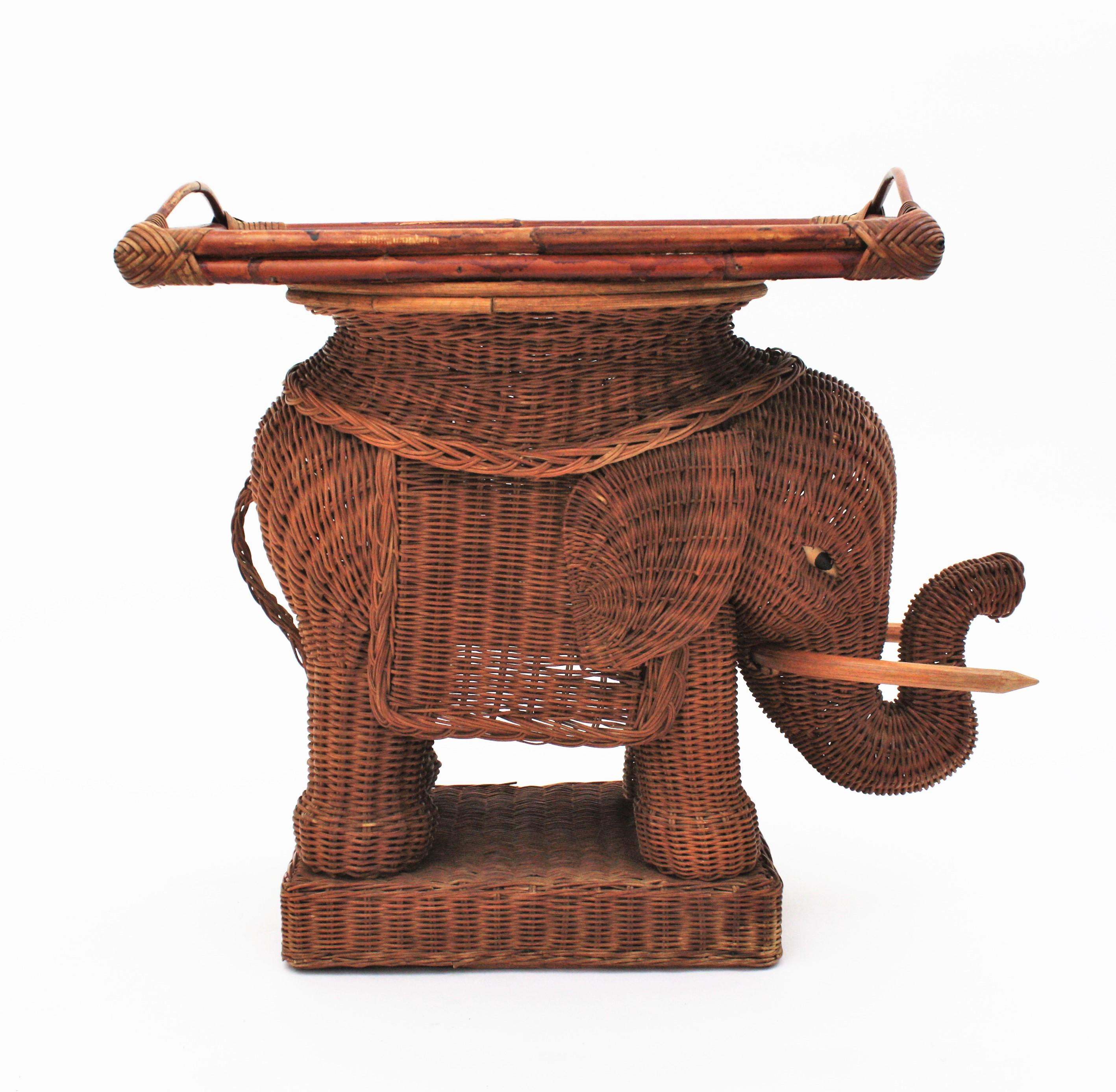 Eye-catching woven rattan end table or drinks table with removable tray top. France, 1940s-1950s.
This elephant shaped end table stand was beautifully constructed in hand braided rattan / wicker accented with wood tusks. The tray top is removable