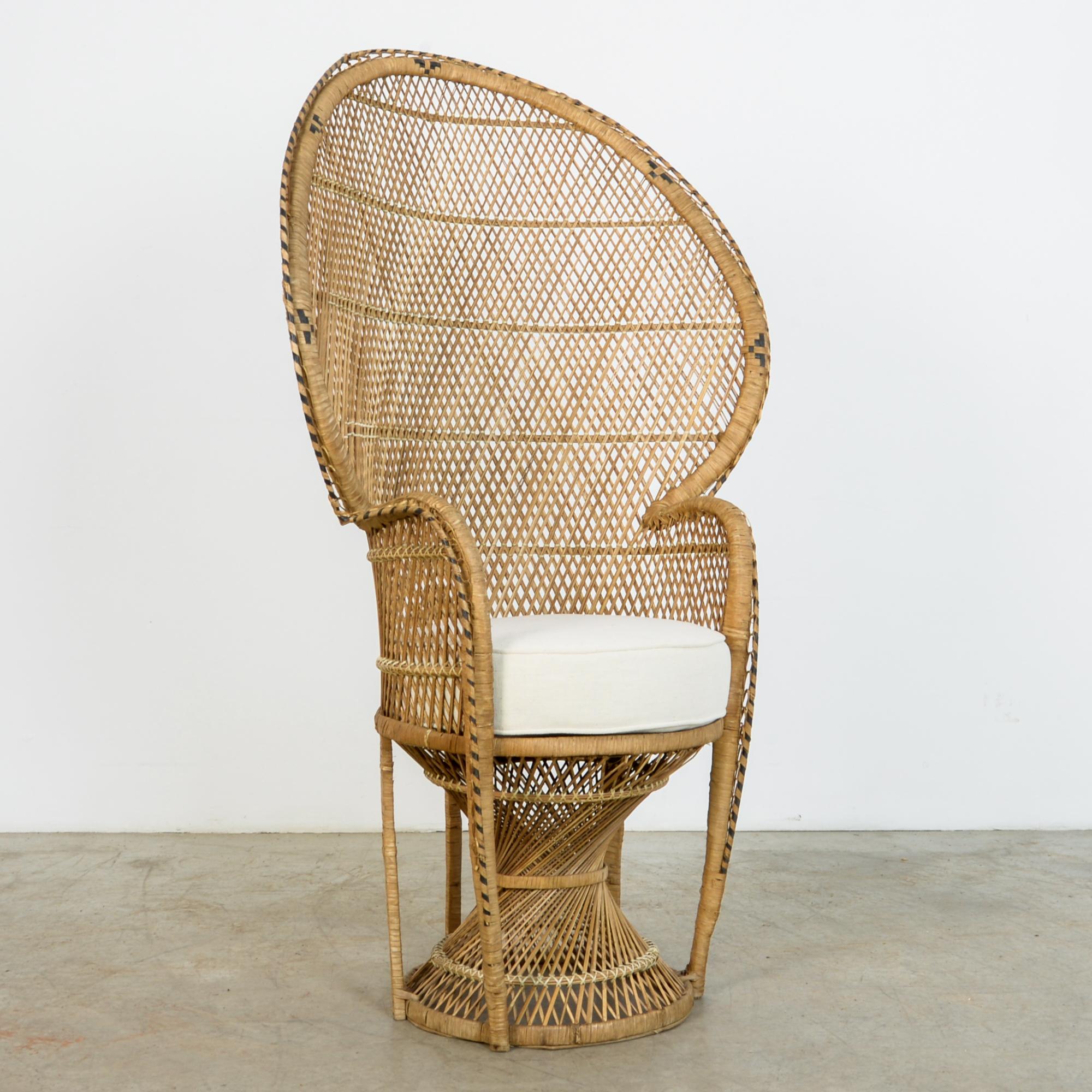 In typical mid-20th century rattan fashion, an “Emmanuelle” style armchair from circa 1960. This throne like chair has a great shape, with black striped ornament and oval back. Topped with a re-upholstered cotton-linen cushion, a casual and fresh