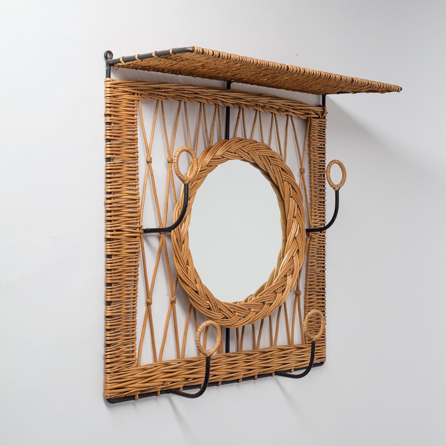 Rare French wall-mounted rattan coat and hat rack with mirror from the 1960s. Blackened steel structure with intricate rattan weaving in varying patterns and original mirror.