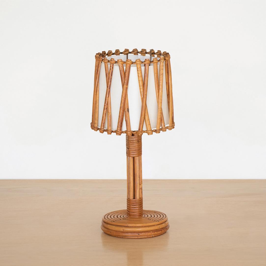 French rattan table lamp by Louis Sognot, 1960's. Circular base and stem with rattan drum shade, crisscross rattan detail and new silk interior shade lining. Newly rewired. 



