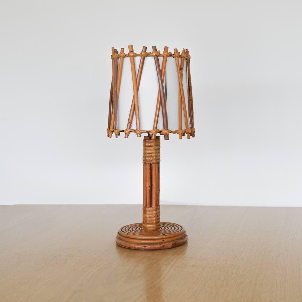 French rattan table lamp by Louis Sognot, 1960's. Circular base and stem with rattan drum shade, crisscross rattan detail and new silk interior shade lining. Newly rewired. Takes one E12 base bulb, 25 W or higher using LED.



