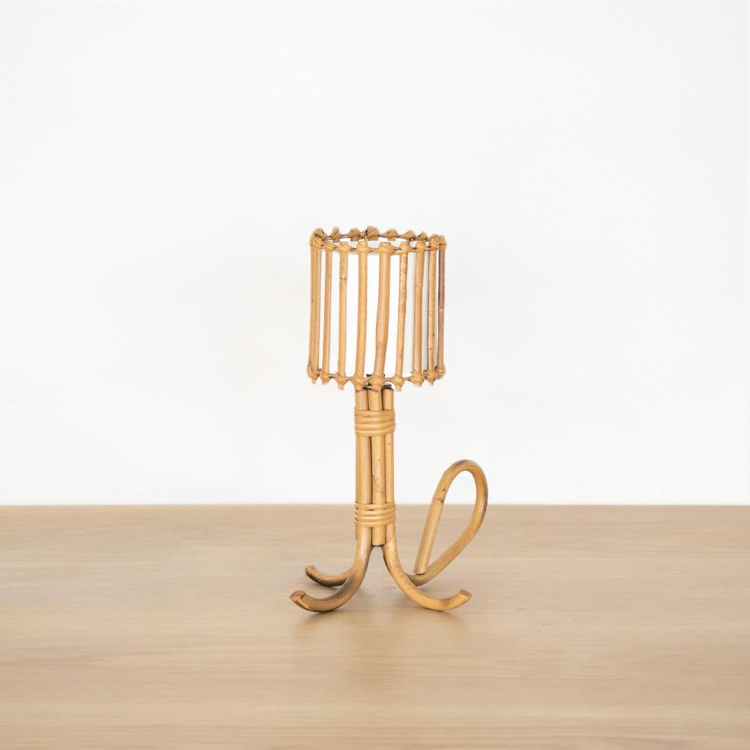 Unique French rattan table lamp in the style of Louis Sognot. Three-leg rattan base, petite drum shade with rattan detail and silk interior shade lining. Newly re-wired. 

Shade measures 4.25