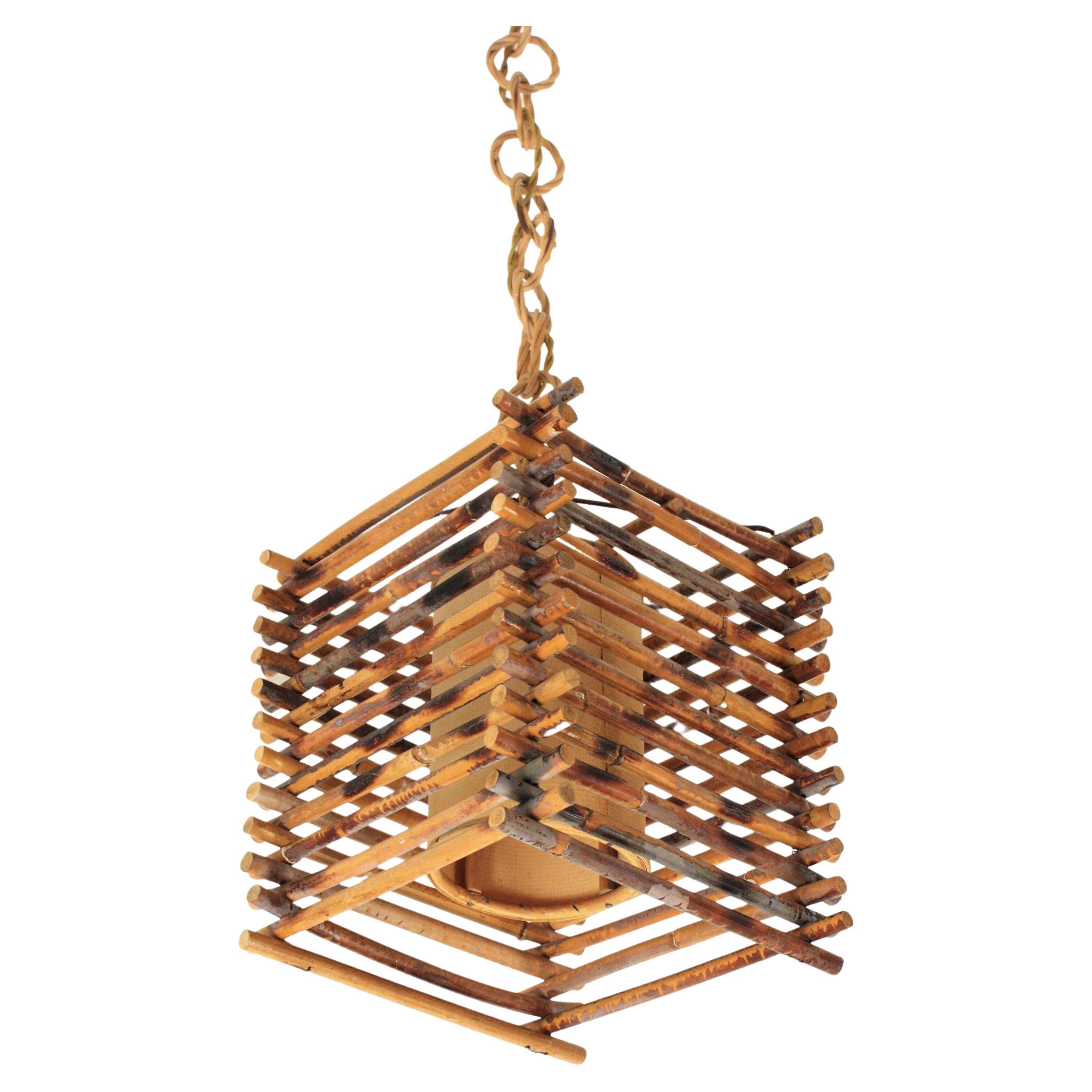 Oriental Inspired rattan lantern. France, 1950s-1960s.
This handcrafted ceiling lamp features a squared lantern made of rattan canes with an inner paper lampshade. The chain is made of wicker rings topped by a wood canopy.
This pendant lamp will