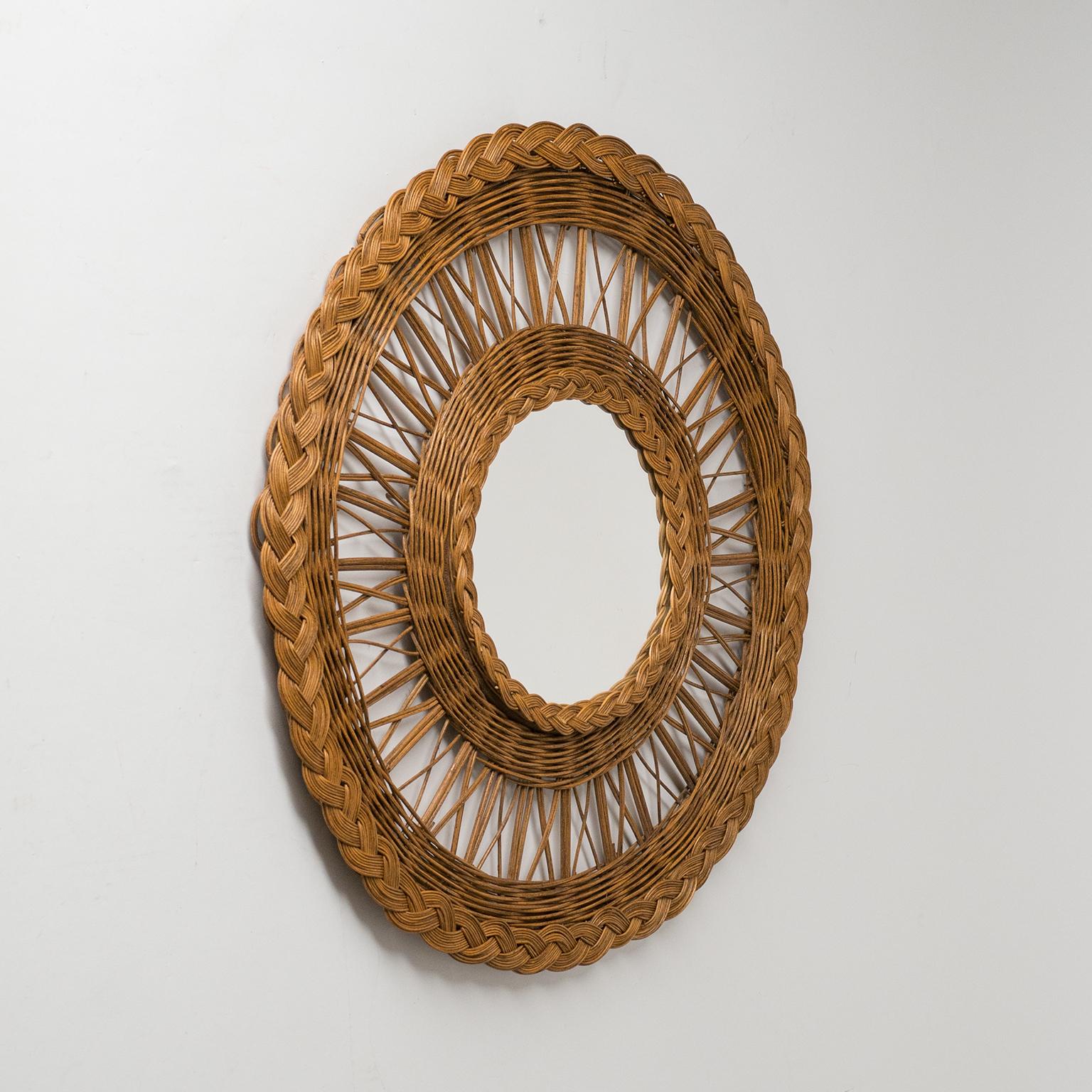 Lovely French midcentury rattan mirror from the 1960s. Rare wheel-shaped design with varying weaving patterns and a nice attention to details. Mirror diameter is 7inches/18cm.