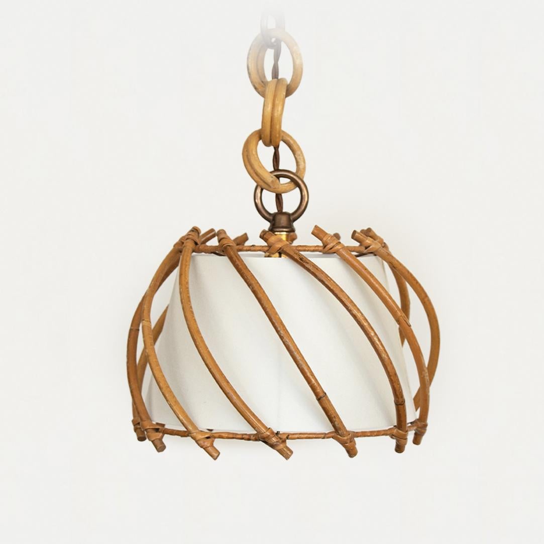 Petite rattan pendant light from France, 1960's. Original shade with diagonal rattan pieces, rattan loop chain and metal frame. New silk interior lining, newly rewired with new brass canopy.
