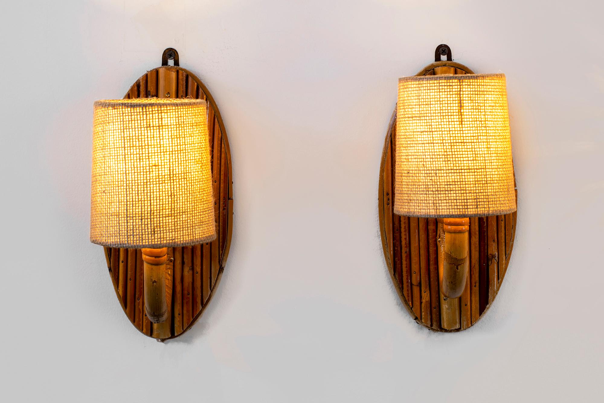 Wonderful pair of French rattan sconces with torchiere arms and textured linen shades. 
Newly rewired.