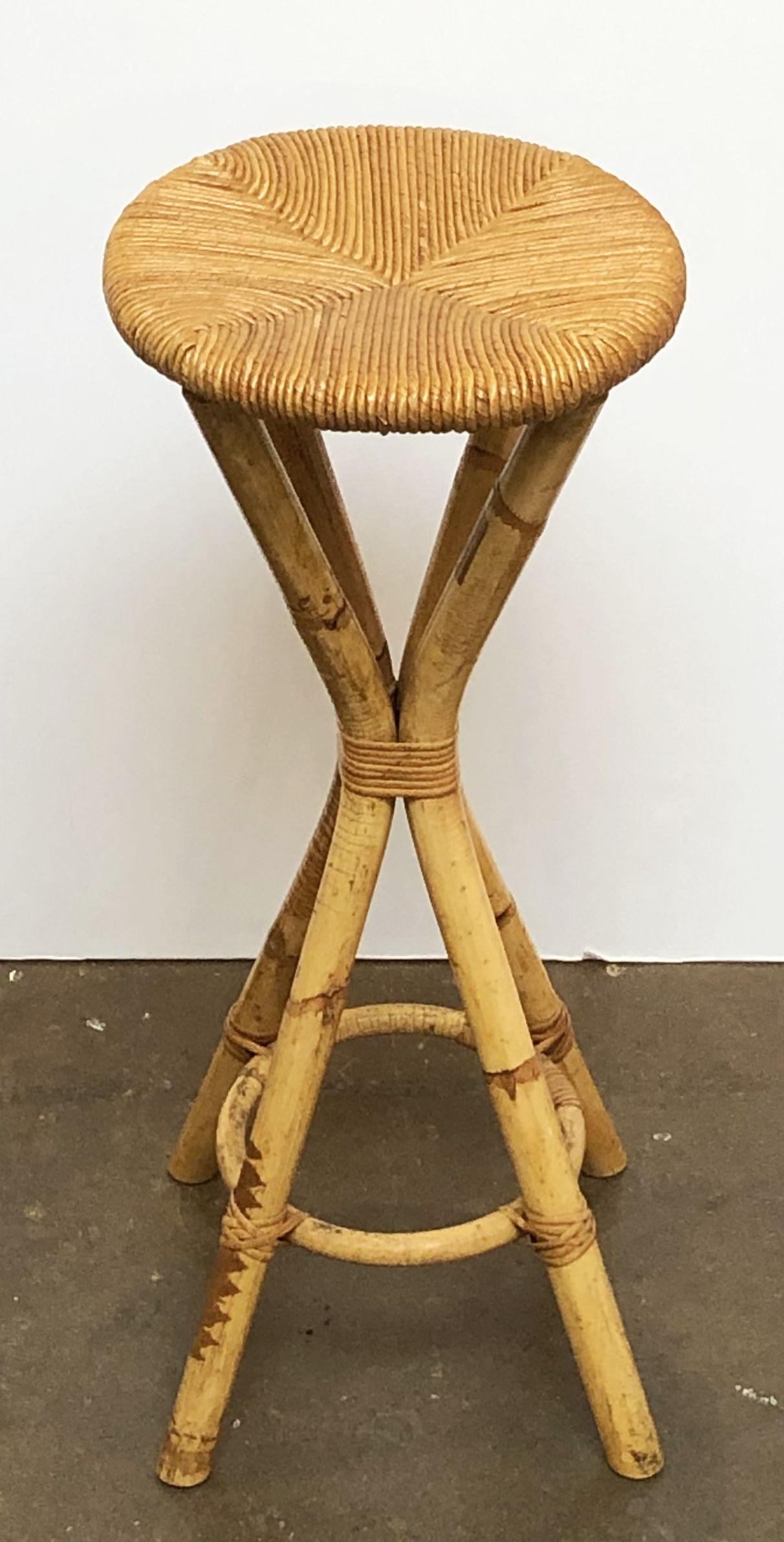 A fine French mid-century bar or seating stool of rattan with a woven rush seat by Le Rotin.