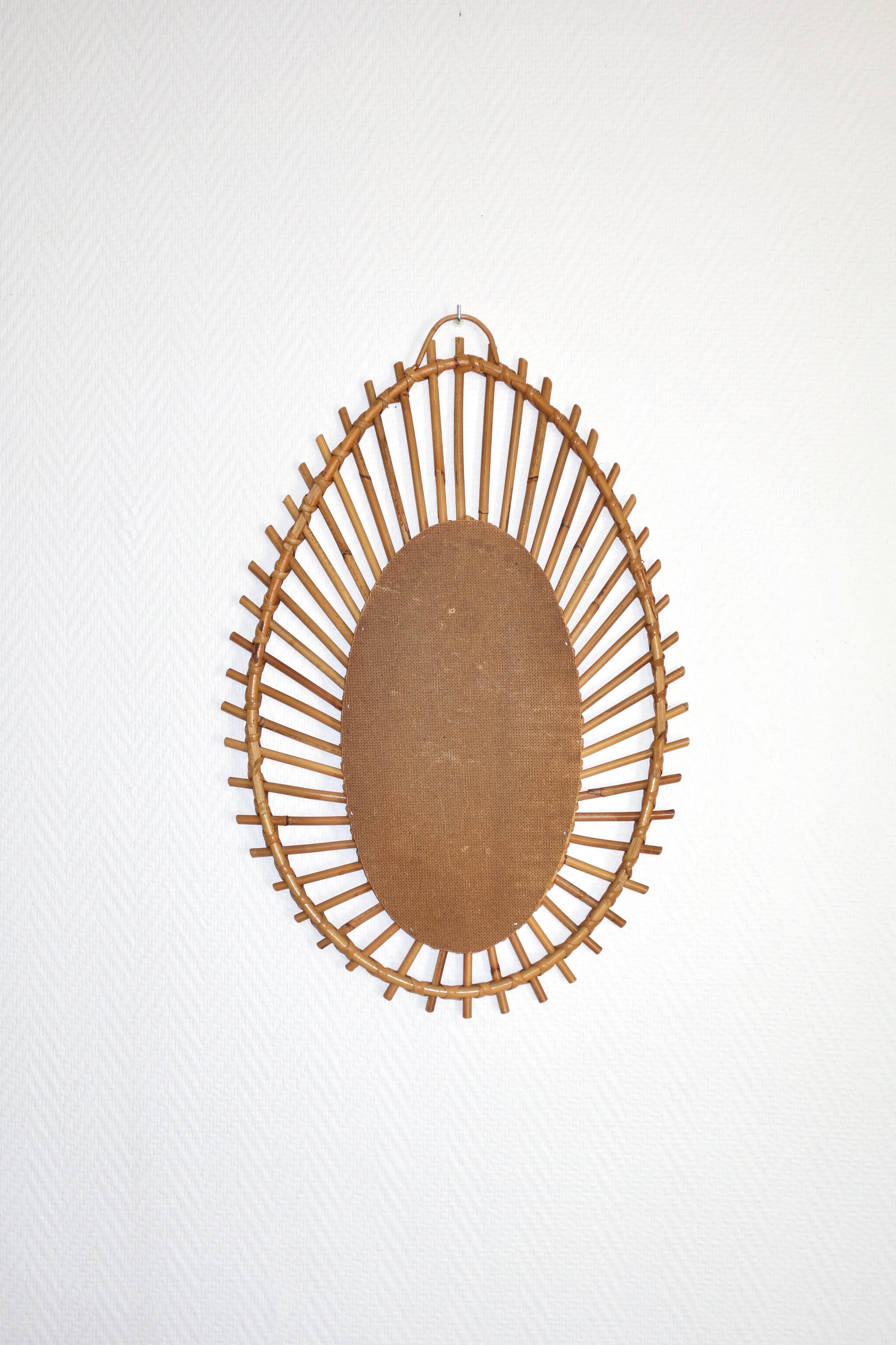 Vintage mirror of freeform rattan. French manufacture of the 1960s. Asymmetrical oval shape, good quality of manufacture. In perfect condition and entirely original. Beautiful patina, wall hanging rattan. Dimensions of the mirror alone : ??height of
