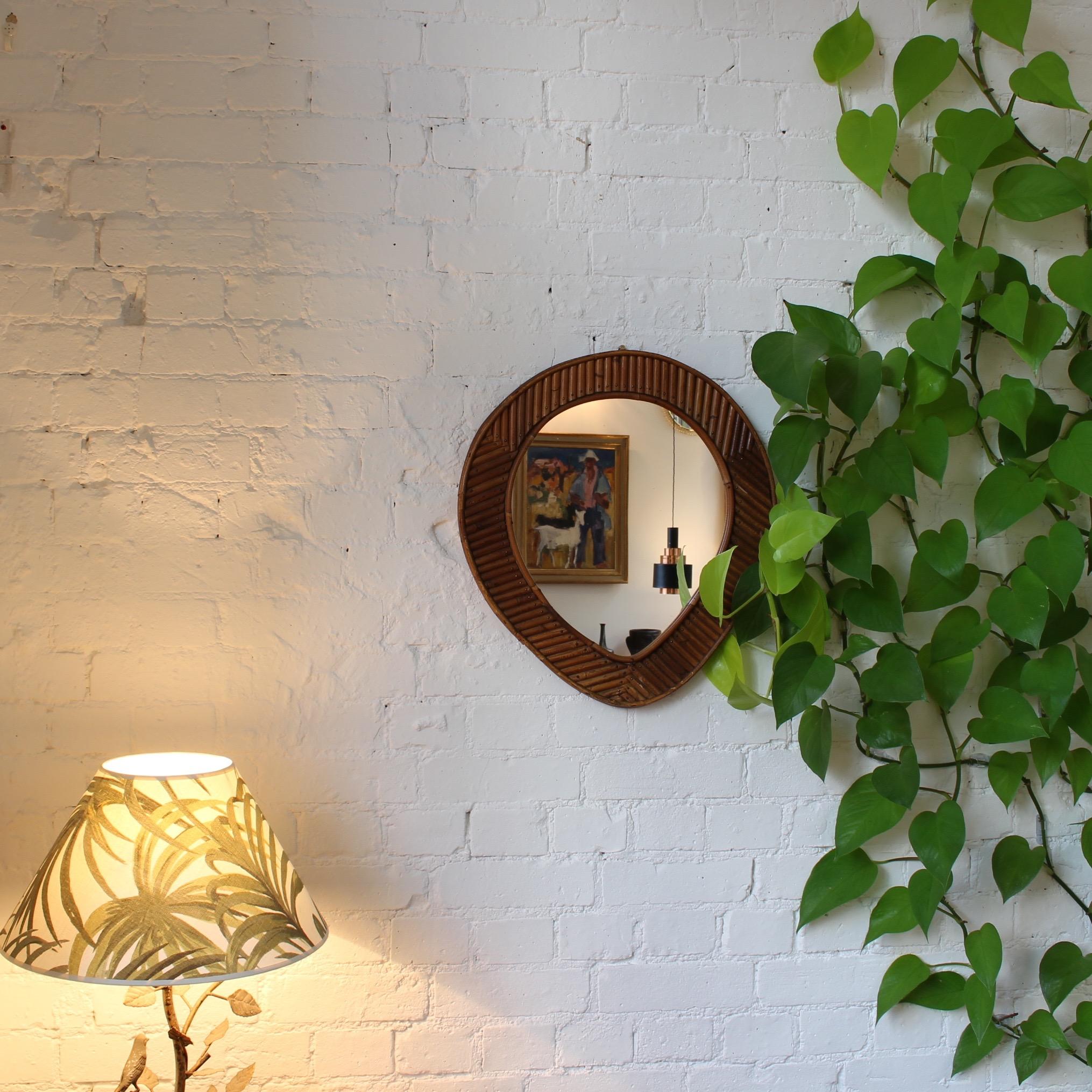 French rattan tear-drop shaped mirror, circa 1960s. The inner and outer circular frames are linked by hand cut and nailed rattan reeds in opposing linear patterns. The mirror is a genuine original and very rare in the realm of vintage rattan design.