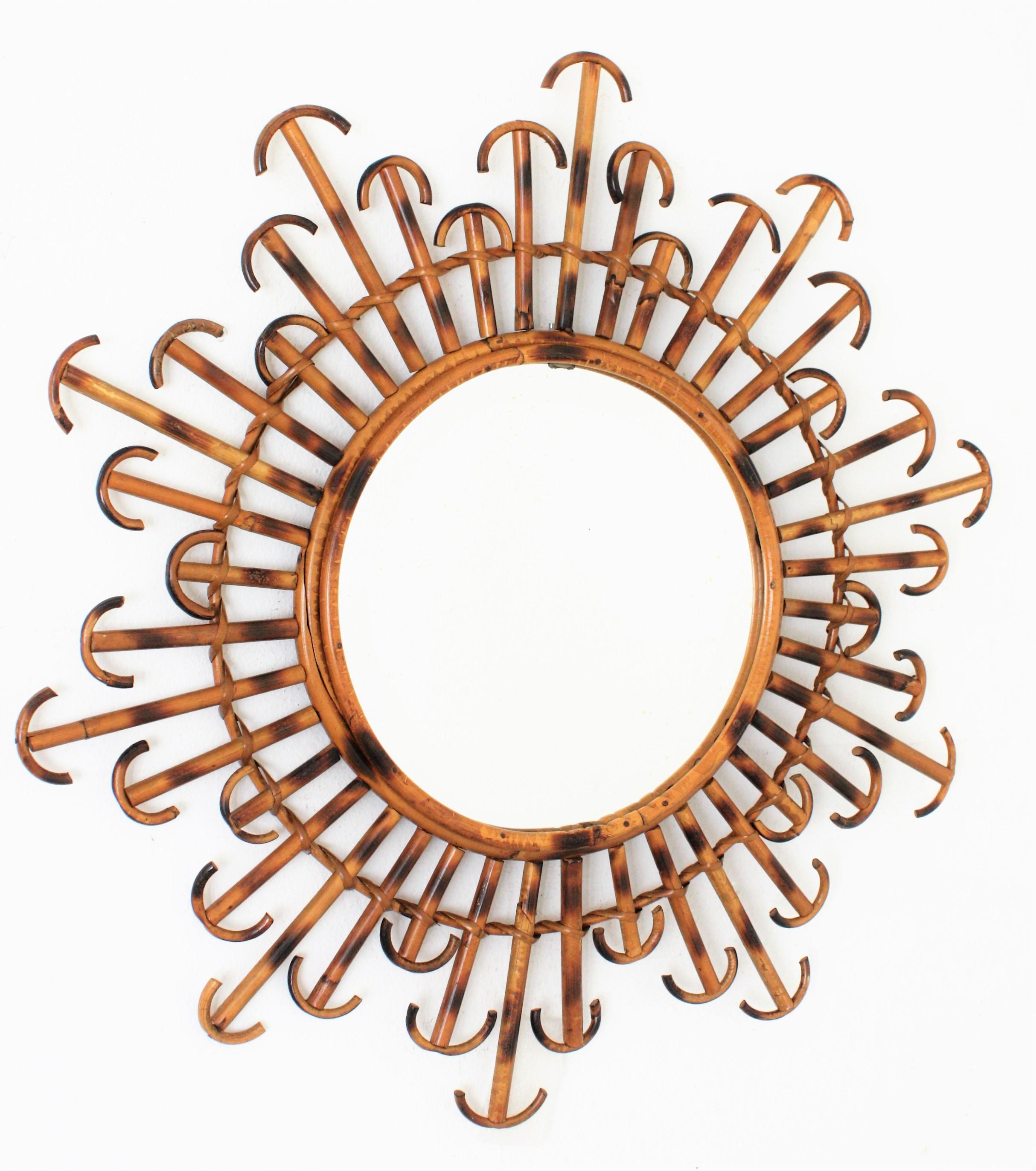 A lovely flower burst or sunburst mirror handcrafted with rattan and wicker with pyrography decorations and curved endings. France, 1950s.
This mirror has three layers of alternating rays in different sizes. Beautiful to place it alone, but also