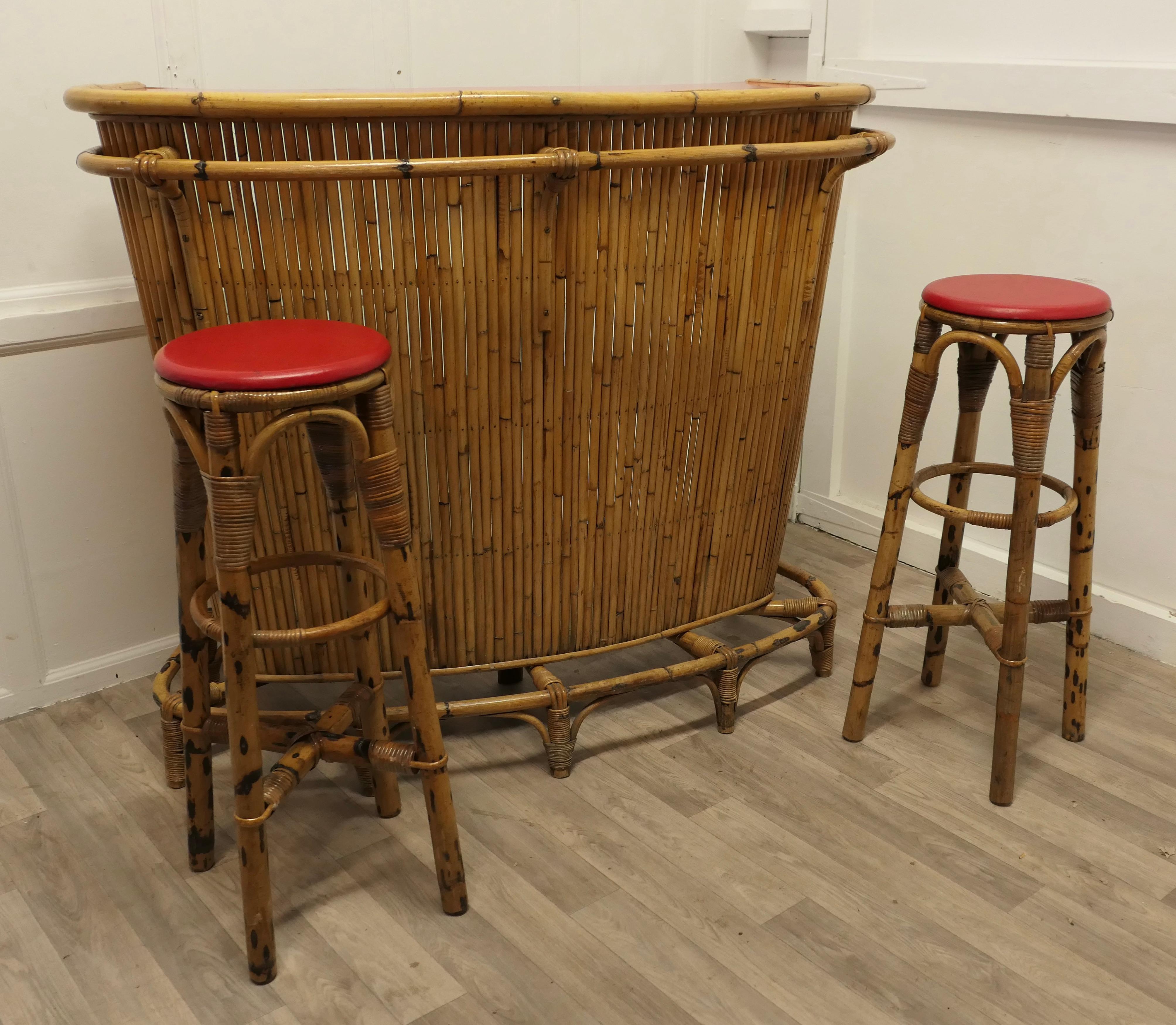French Reception Greeting Tiki Bar with Stools

This is a very lively Retro piece with matching stools, the set is made in bamboo with red vinyl seat covers and formica bar top, a classic of their time
The curved bar has both a foot and an elbow