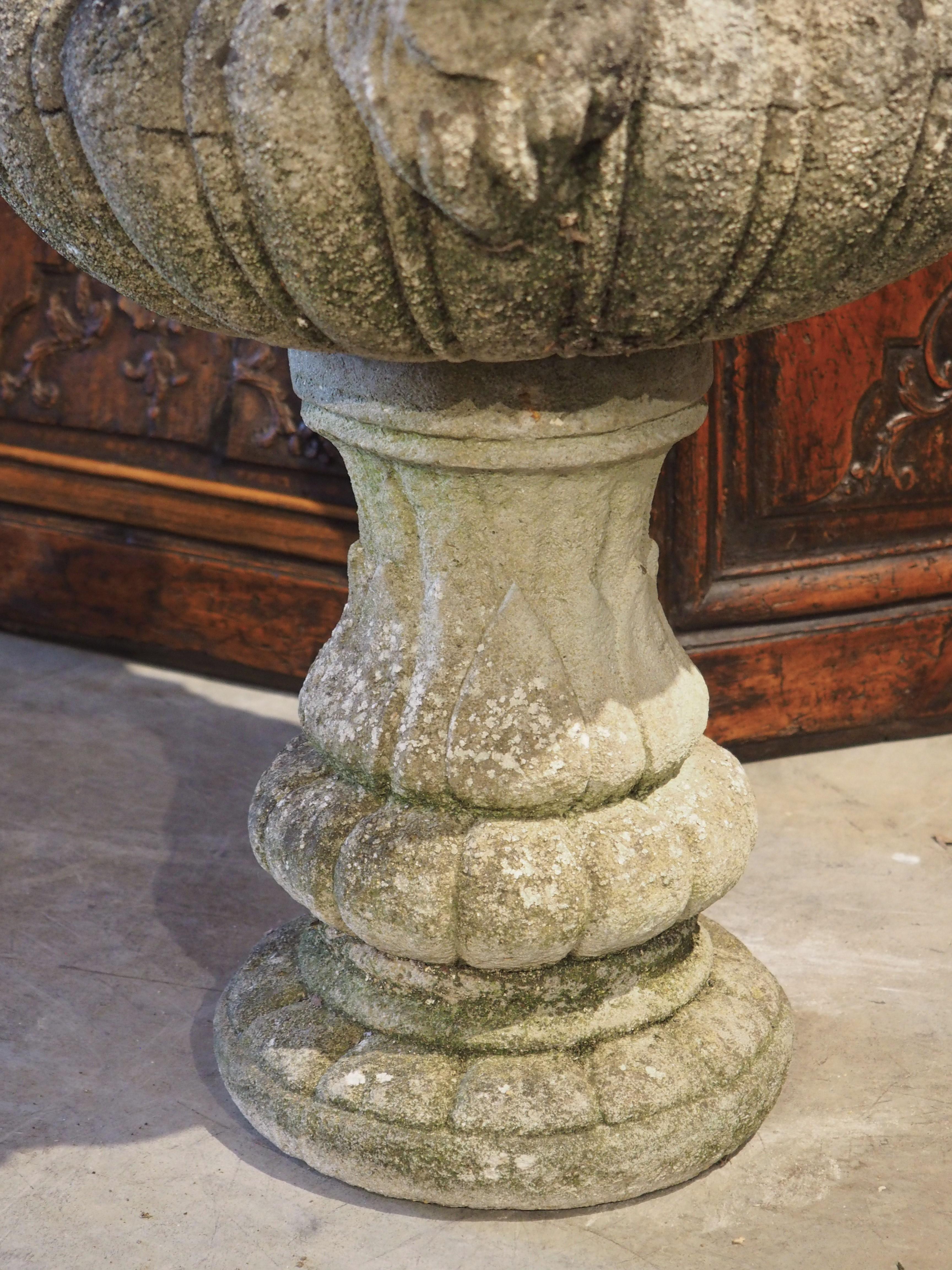 Diese um 1900 aus rekonstituiertem Stein hergestellte französische Vase aux beliers (Vase mit Widdern) wurde in zwei Teilen gegossen. Der Hauptteil ist mit dicken Gadroon-Lappen unter einem tiefen Kavetto-Gesims verziert, das von zwei