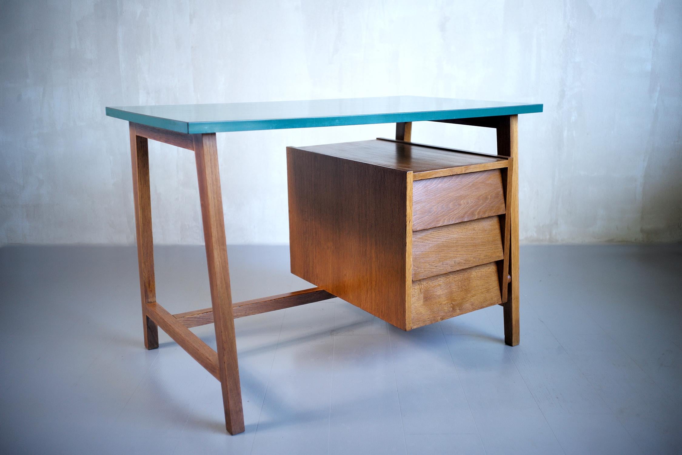 Desk attributed to Alain Richard, French Reconstruction 1950. The top is veneered with green Formica, the base and the fronts of the drawers are in solid oak, the structure of the box is in oak veneered slatted plywood. The box with three large