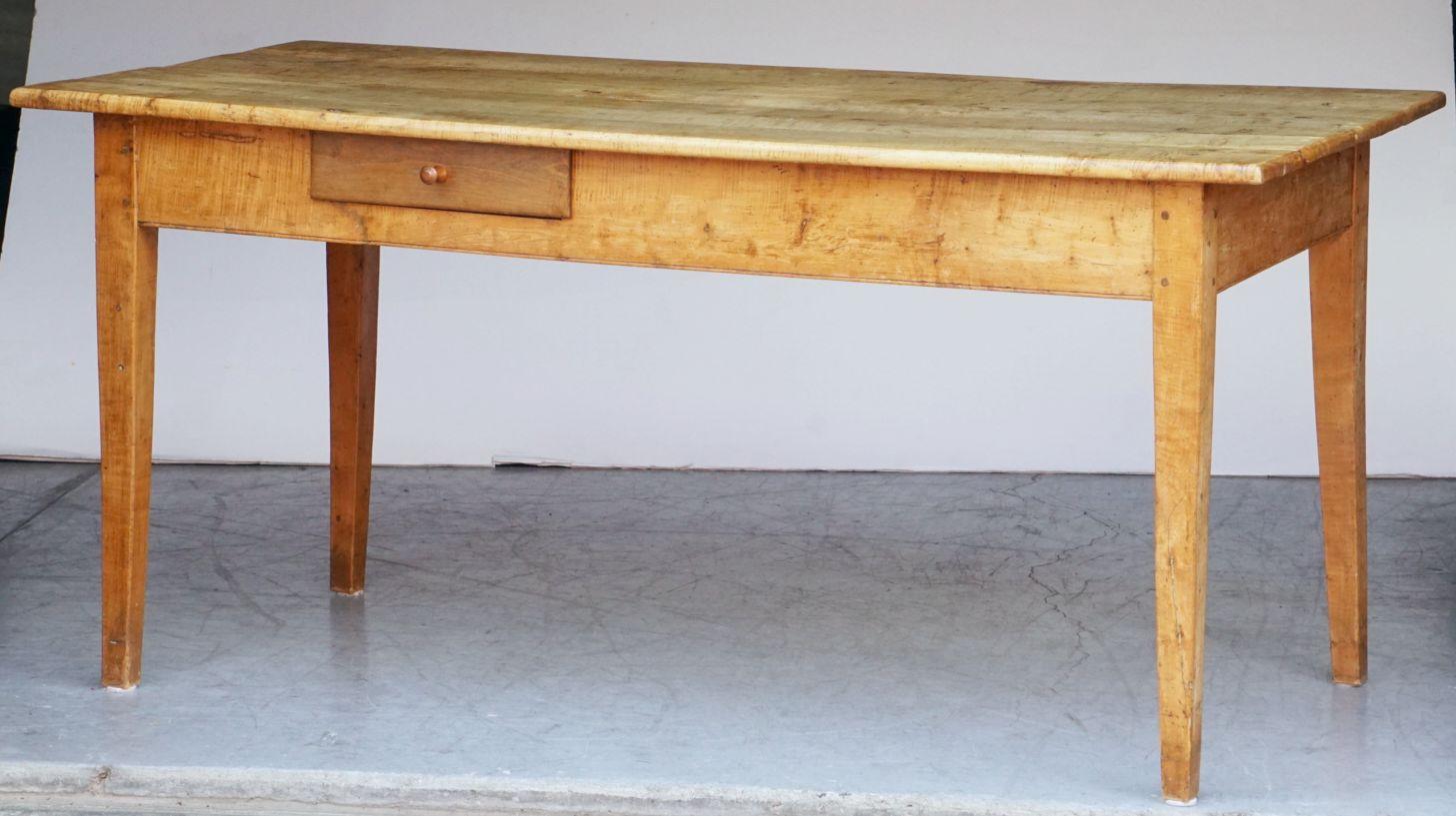 A handsome French rectangular farm table featuring a figured sycamore top over a frieze with a single drawer to one side, resting on square tapering legs.