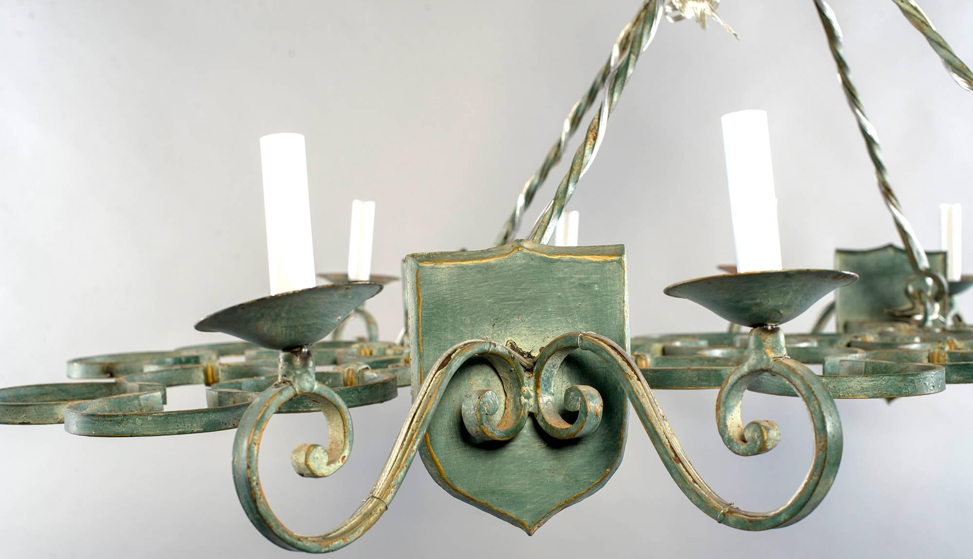 French iron chandelier has scroll work rectangular base suspended by chain with eight candle style light, circa 1920s. New wiring for US electrical standards.