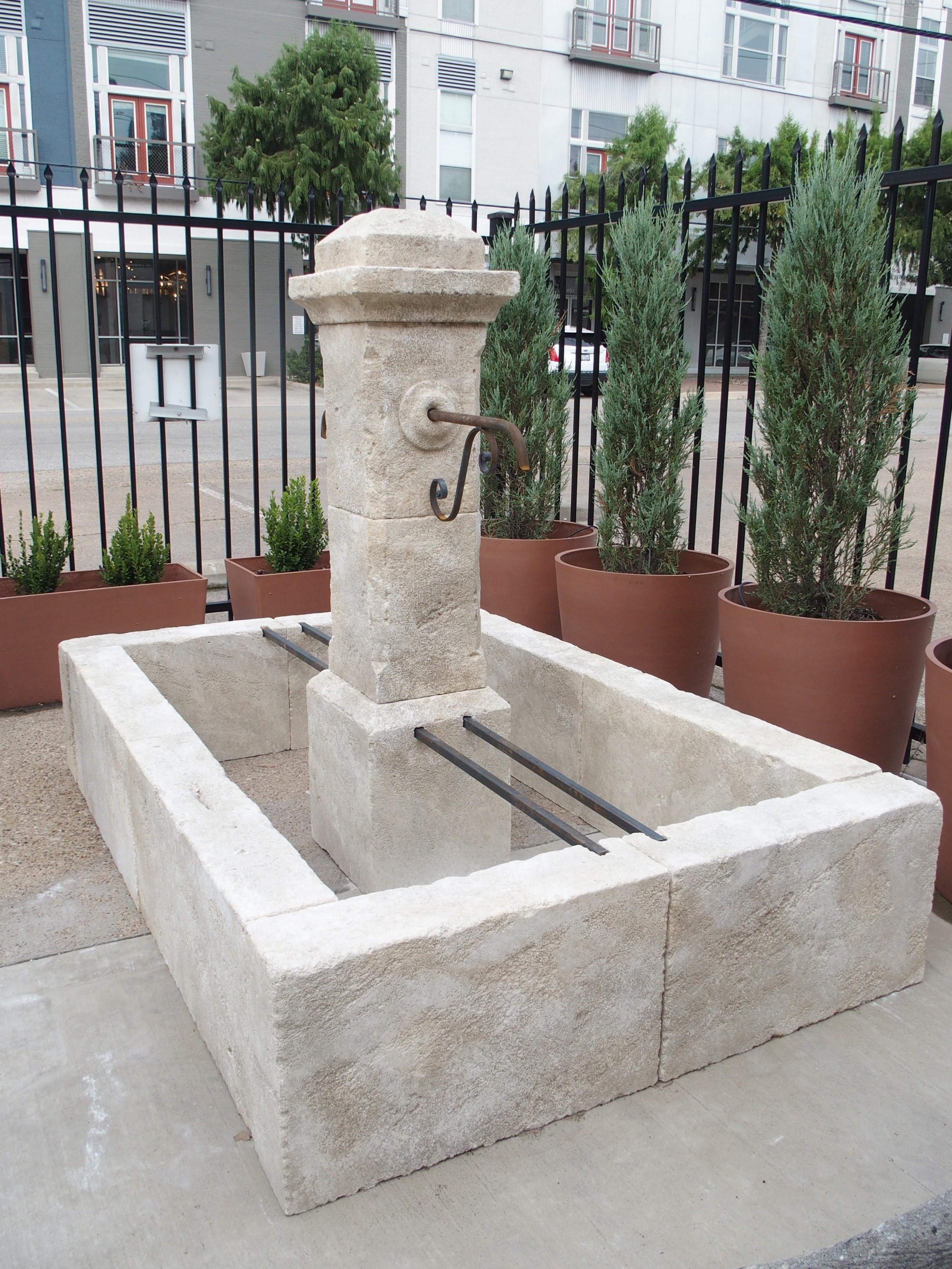 Hand-carved in France from 13 pieces of Estaillade limestone, this rectangular center fountain with two scrolled iron spouts would make a wonderful addition to a courtyard or outdoor landscape. The rectilinear basin is softened by the subtly carved