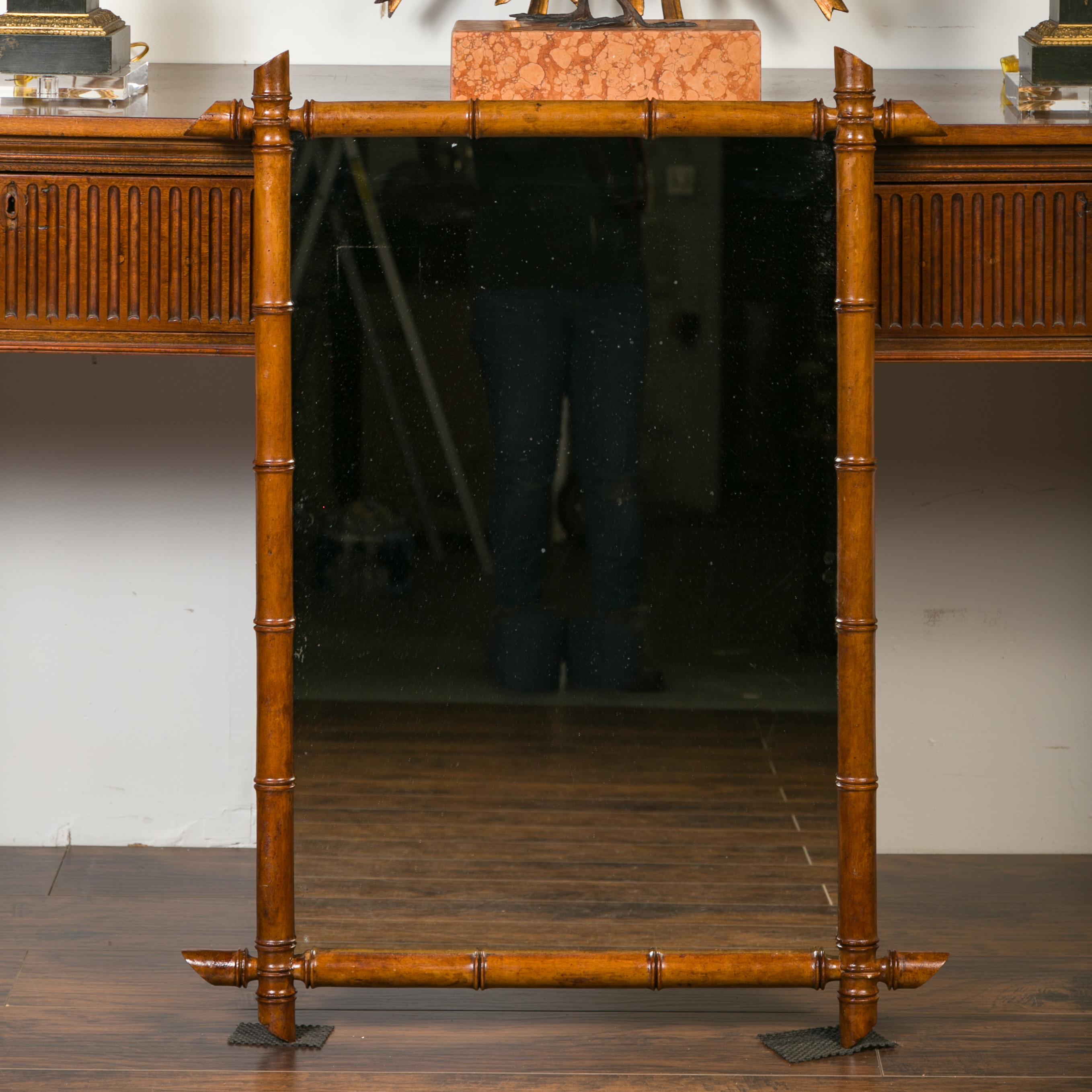 A French rectangular faux-bamboo walnut mirror from the early 20th century, with honey brown patina. Born in France during the early years of the 20th century, this rustic mirror features a rectangular silhouette made of a thin brown faux bamboo
