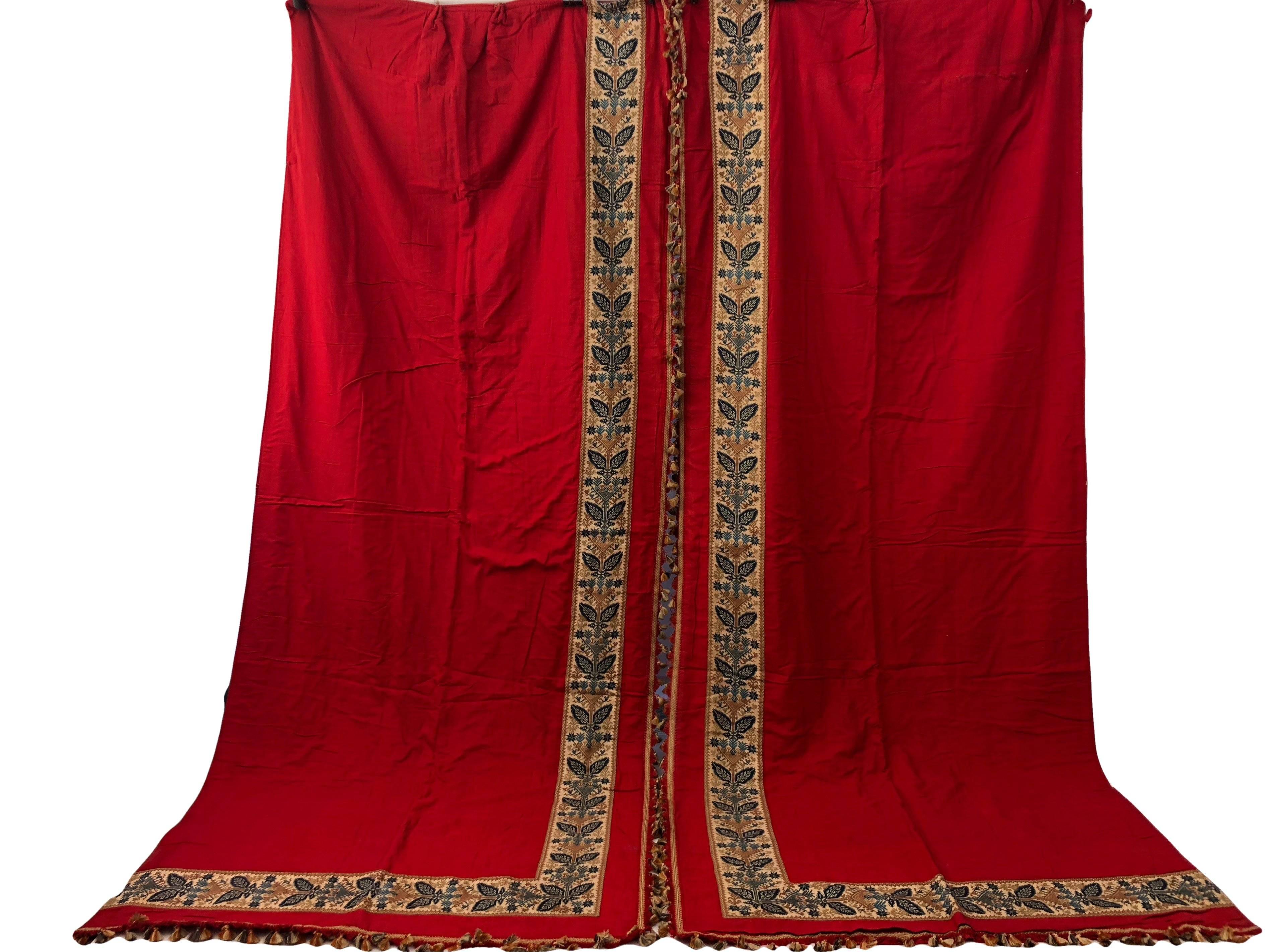 This is a beautiful set of French padded red curtains with a gorgeous weaved trim and fringe tassels. The color is a rich, elegant red and the trim band is wide and multicolored with a blue and tan motif. The tassels are multicolored in red, tan and
