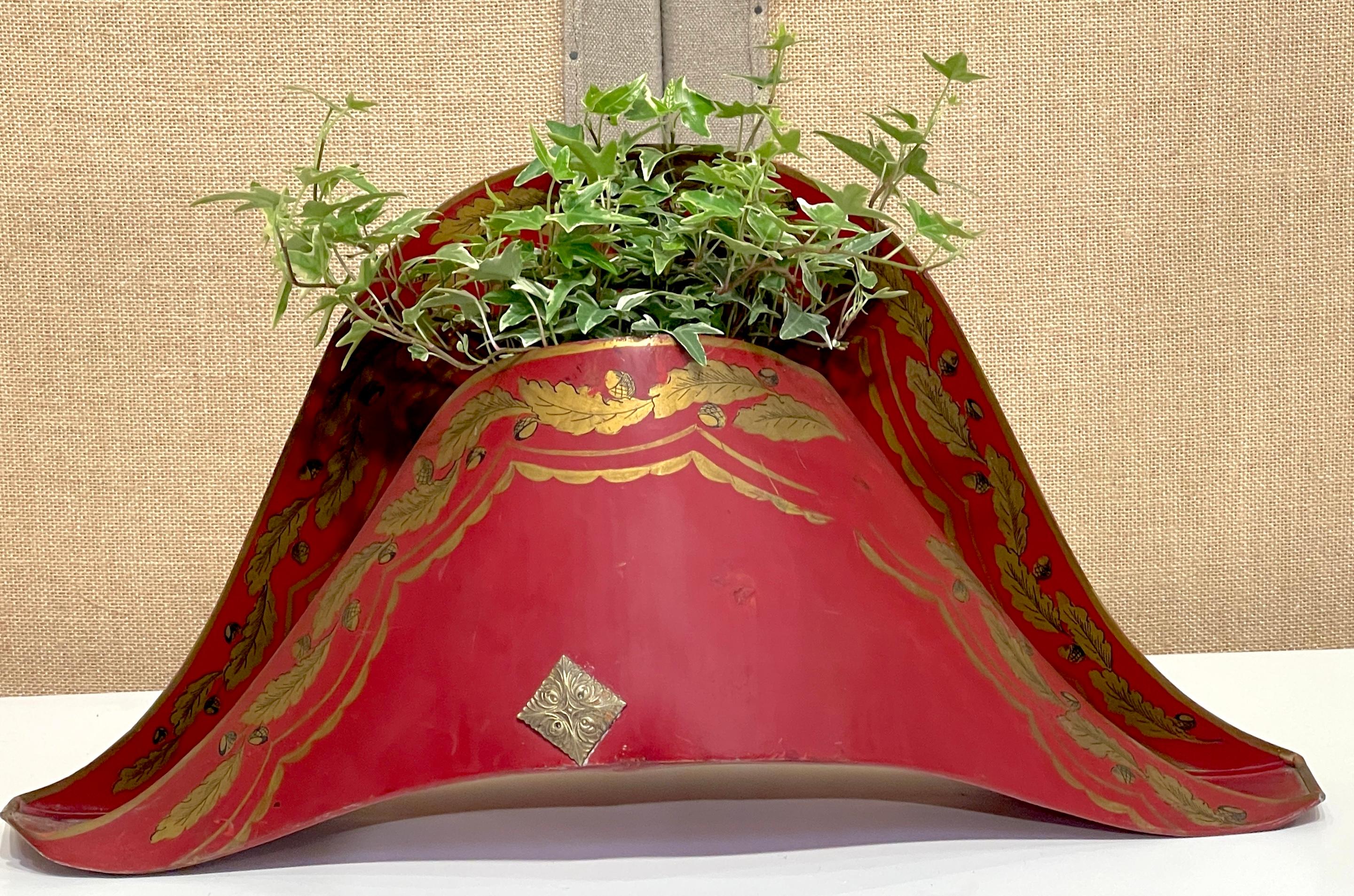 French Red Gilt-Decorated Tole and Bronze Planter/Cachepot of Napoleon's Hat, France, 1950s

This whimsical French planter, crafted in the 1950s, is a delightful homage to the iconic bicorne hat of Napoleon. Made of vibrant red tole, it features