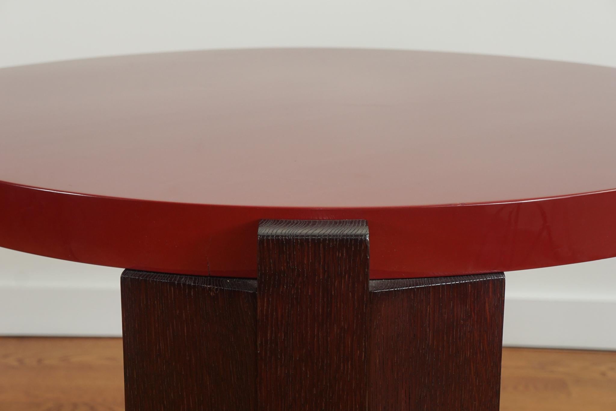 The coffee table shown here is as distinctive for its design as it is its lacquer and wood finishes.  Signed by Ducarroy, the oak round coffee table features a red lacquer top and feet with rich, ebony stained legs.   It is classic in every respect