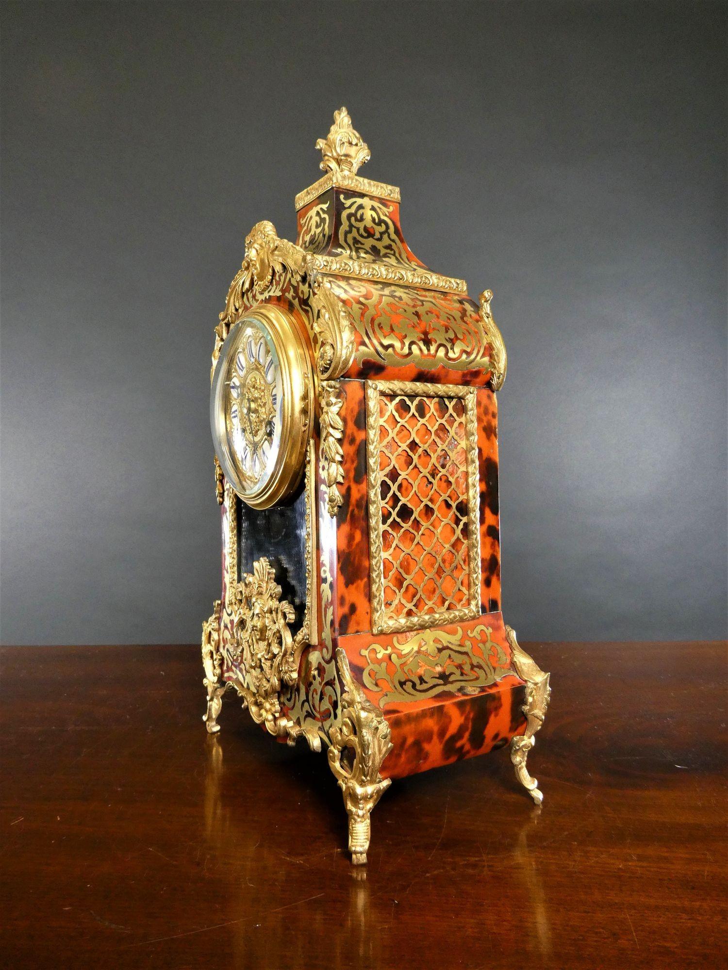 Französische Boulle-Uhr aus rotem Schildpatt, Samuel Marti, Paris.
 
Rotes Schildpattgehäuse mit feinem Messingdekor, überragt von einem Ormolu-Finial, Ormolu-Beschlägen und auf erhöhten Klammerfüßen stehend. Die Vorderseite des Gehäuses mit