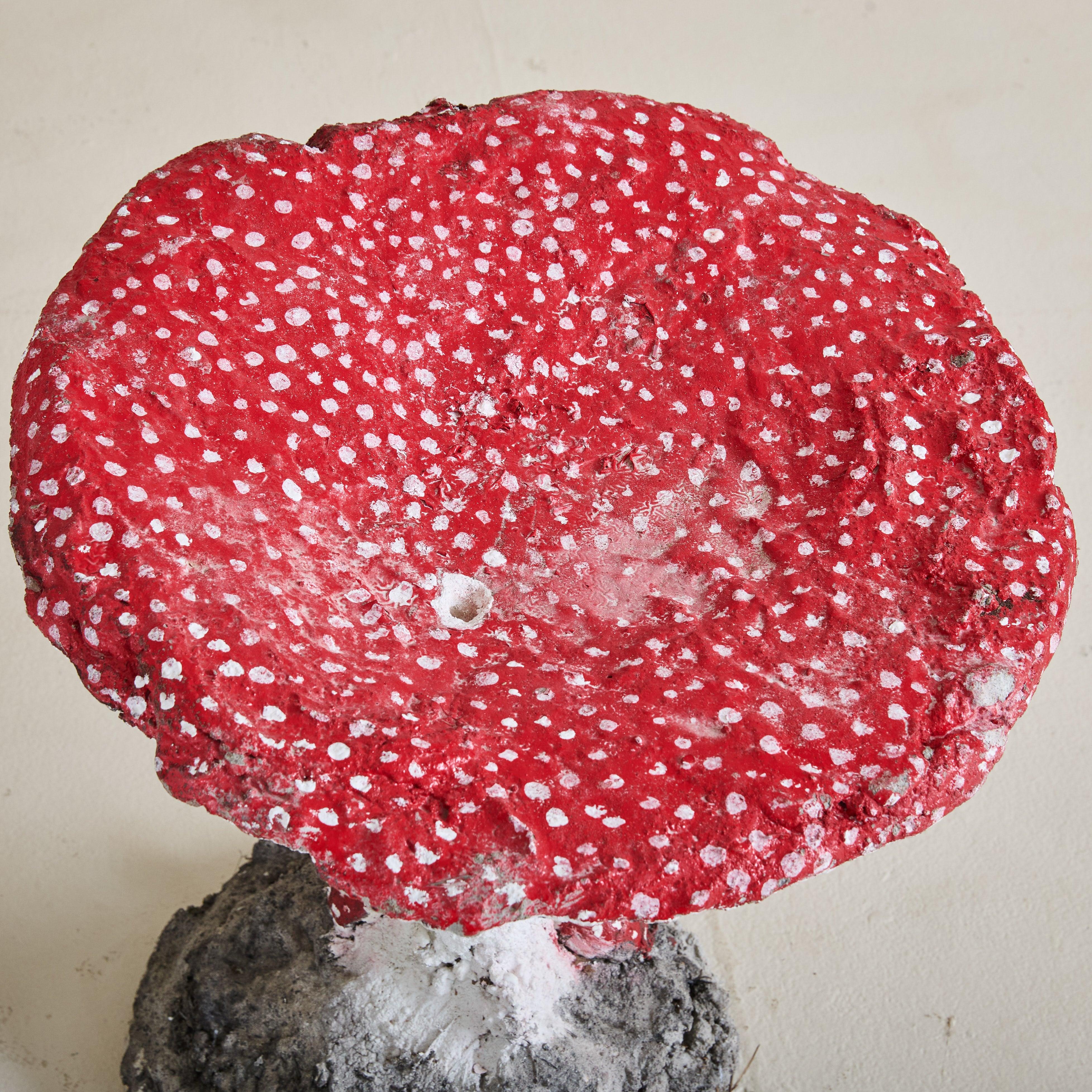 Sgabello o scultura da giardino in cemento dipinto a mano degli anni '60, caratterizzato da una parte superiore a macchie rosse e bianche e da piccoli funghi decorativi lungo la base. Questa decorazione da giardino può essere utilizzata sia