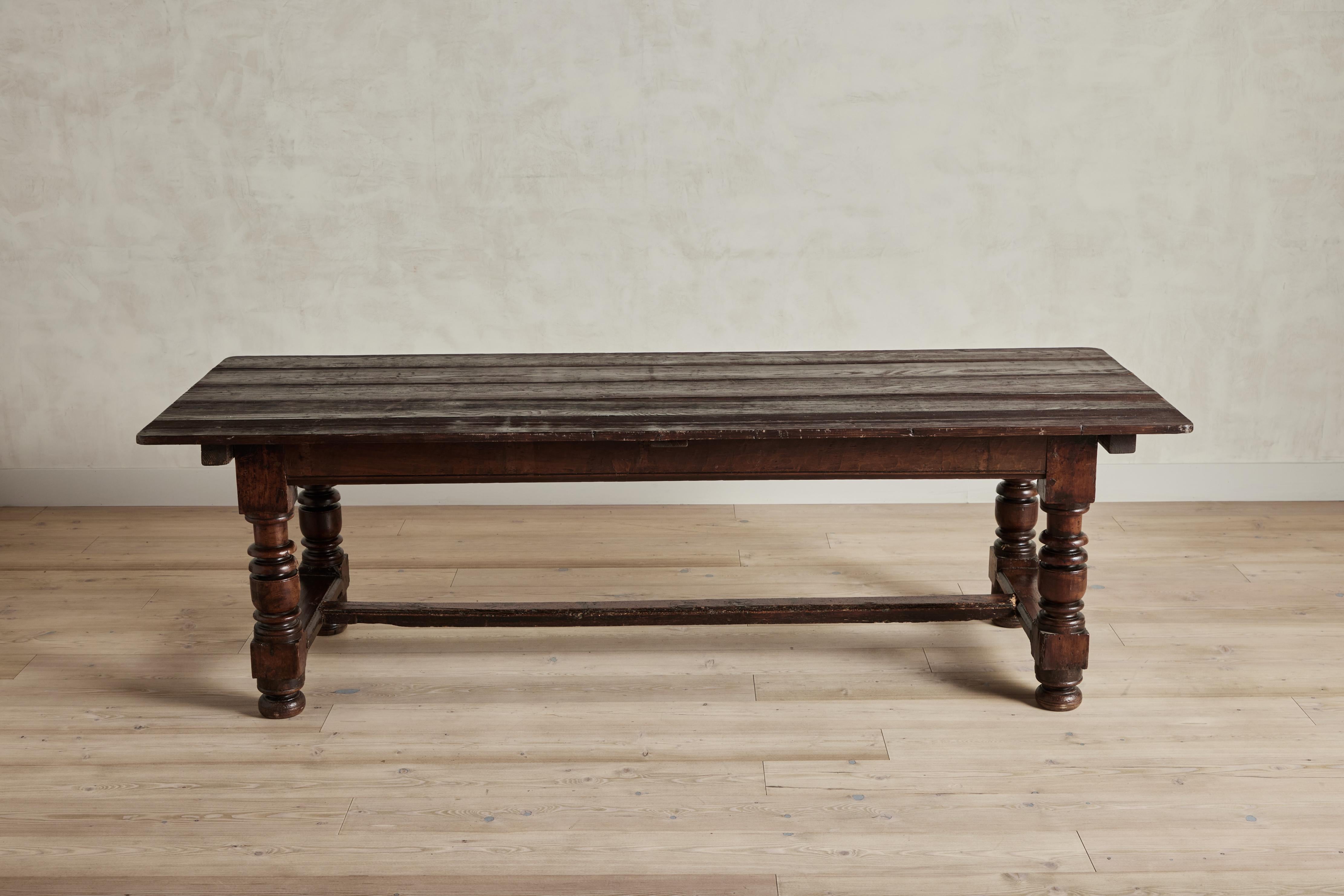 19th century refectory dining table with ornate turned wood legs in a dark wood finish. Good vintage condition with some visible wear on wood and finish that is consistent with age and use.