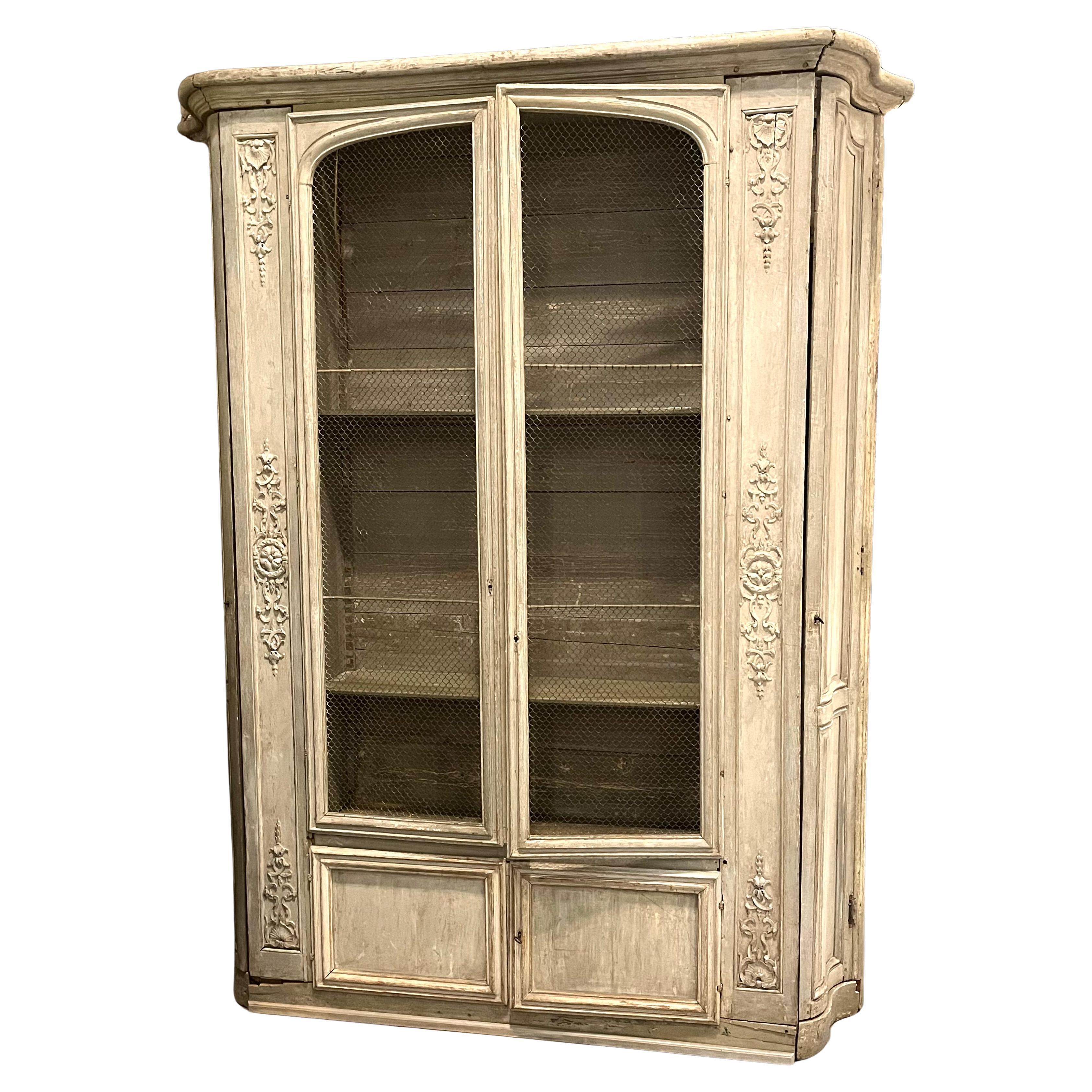 A rare French Régence period biblioteque, circa 1740, with arched wire-inset doors over two lower square paneled doors with adjustable interior shelves, “galbe” paneled side doors concealing additional shelves, the piece is beautifully carved with