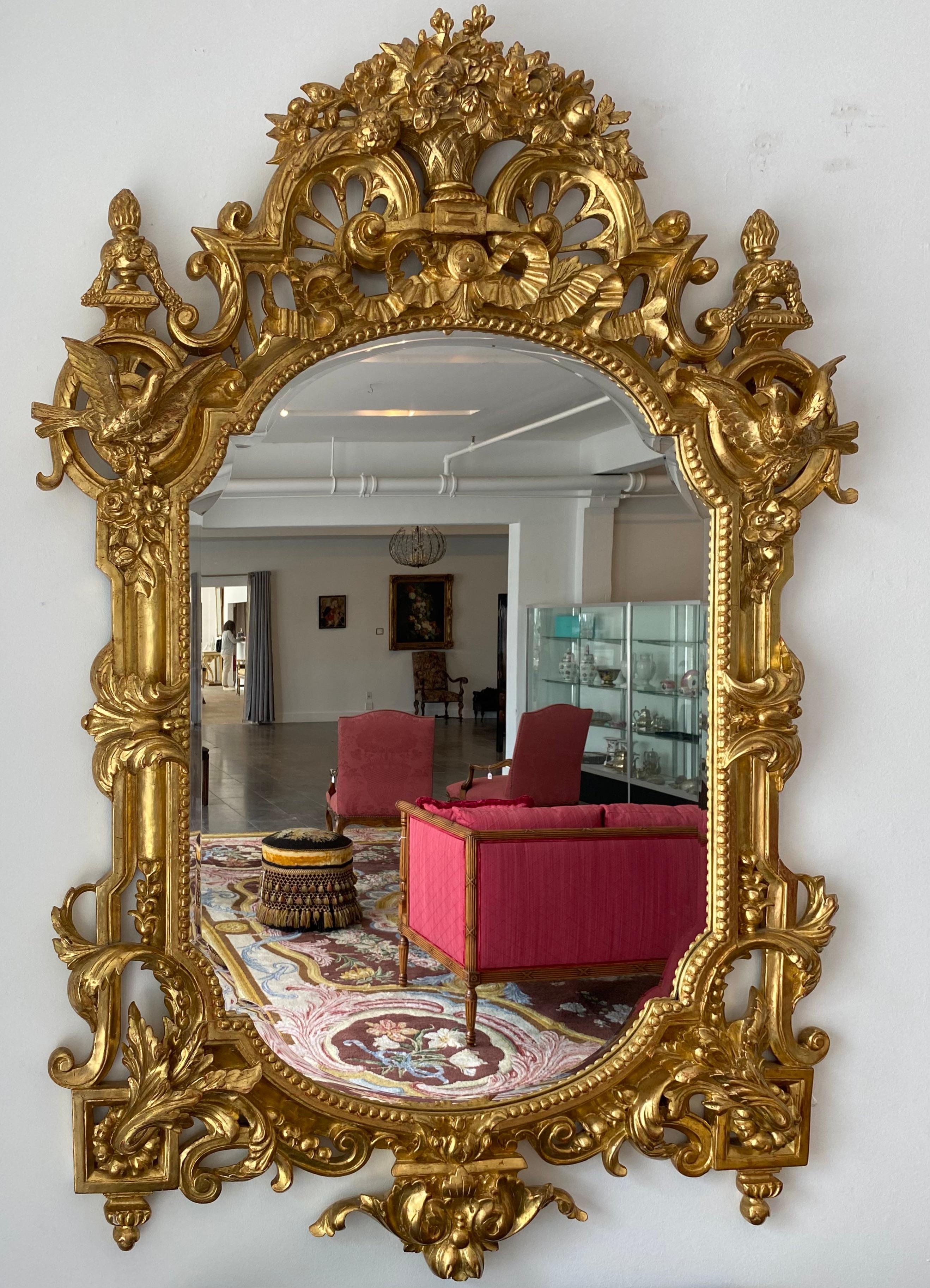 Un beau et très généreux miroir en bois doré de la Régence française, avec des vases, des oiseaux et d'extraordinaires éléments sculptés à la main.

Miroir en bois doré de la Régence française du début du 20e siècle, rappelant les consoles ou