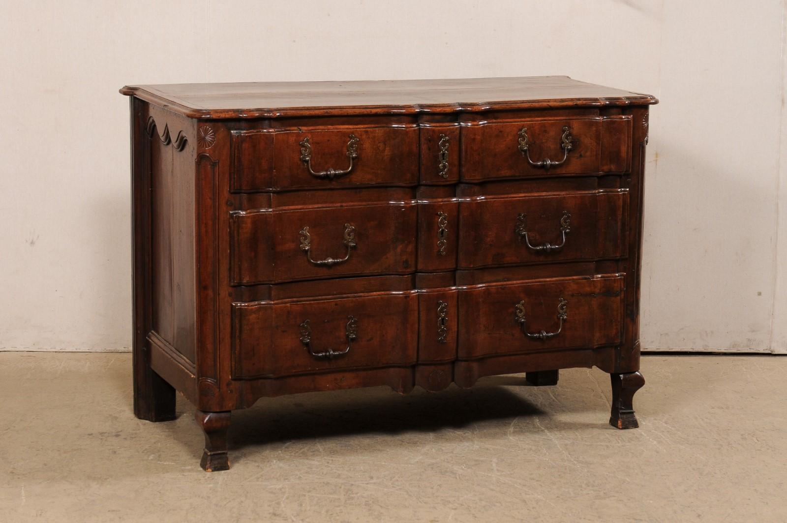 A French Regence period beautifully-carved walnut chest of drawers, with its original hardware, from the 18th century. This gorgeous antique commode from France has been exquisitely carved with a serpentine 'linen-fold' design which goes from the