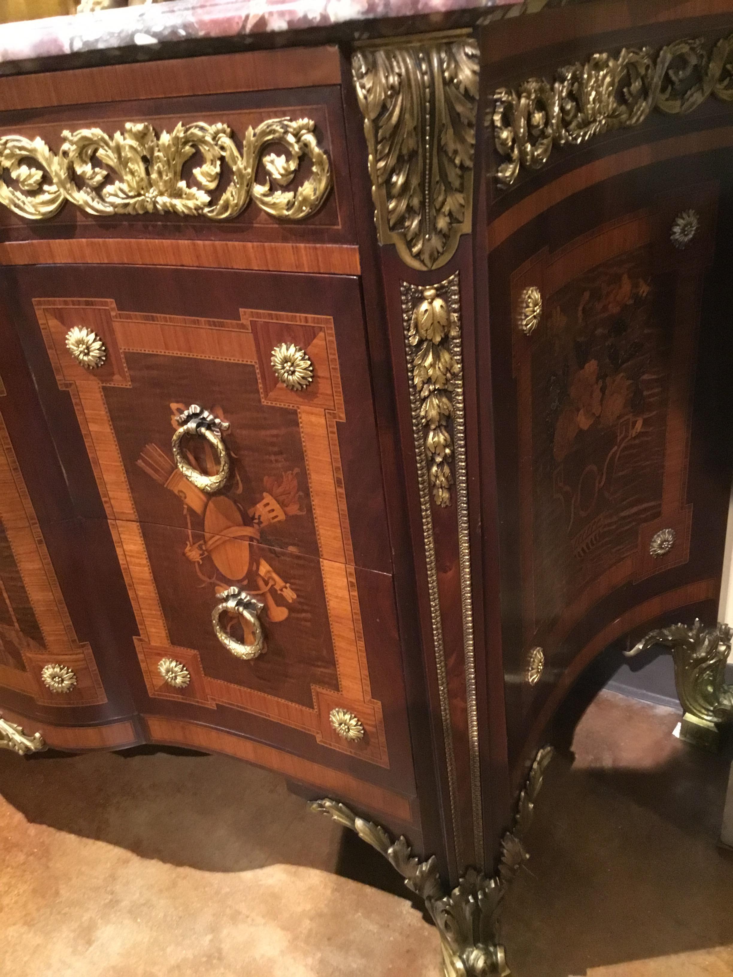 French bronze and Marquetry commode. The original crafted by ebineste Reisner for the Louvre
Palace. Very fine quality overall having a shaped marble top with shades of mauve, cream and
gray hues. The commode utilizes exotic woods of kingwood,