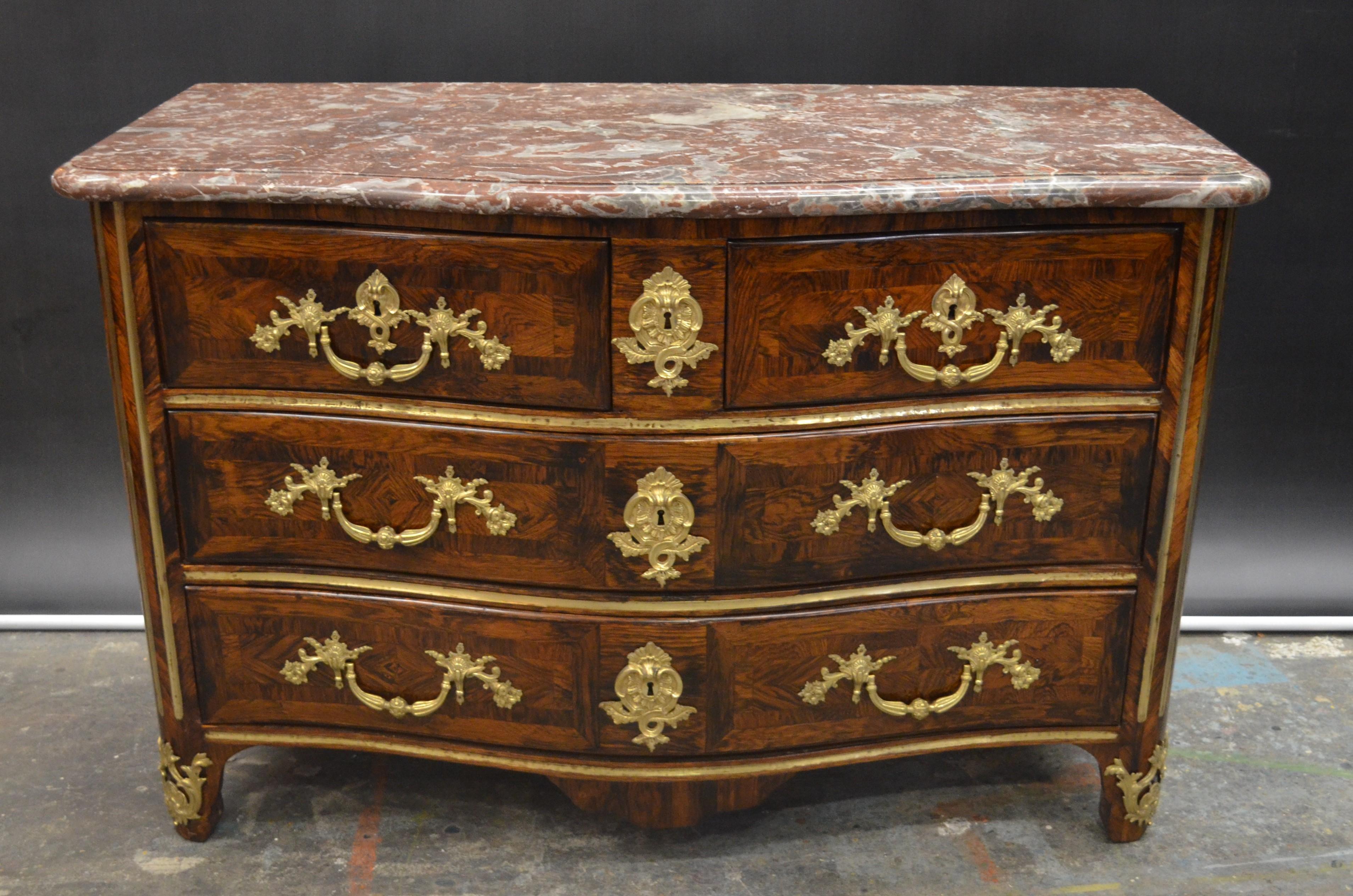 This impressive, 18th century, French Régence Ormolu-Mounted Rosewood & Kingwood veneered Commode retains it's original hand chiseled serpentine front rouge marble-top. This Régence Commode has five drawers with herringbone, and crossbanded inlaid