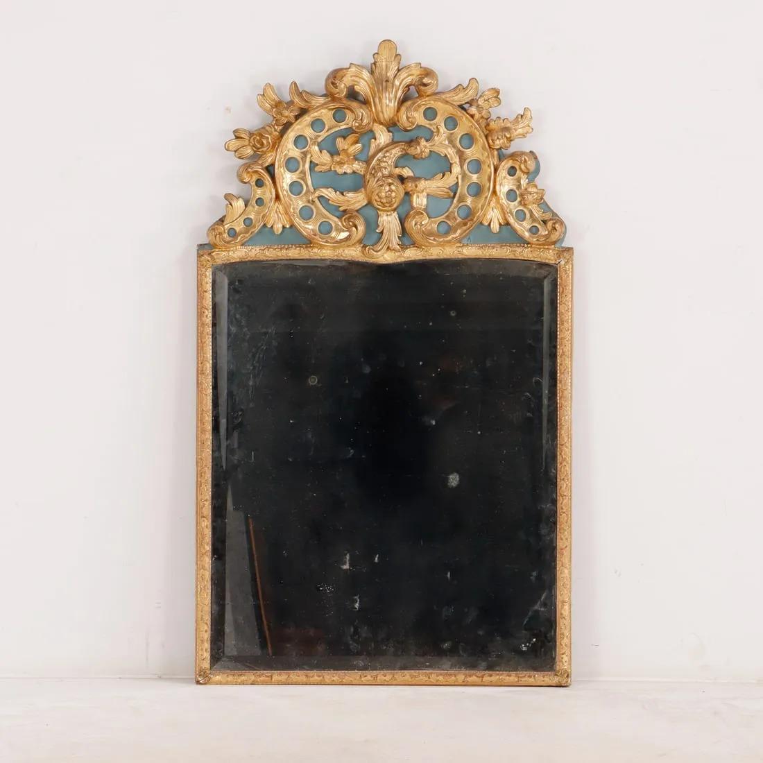 Espejo francés de madera dorada pintada y tallada de la Regencia, de hacia 1780, con una cresta tallada con elaborados volutas y follajes sobre una placa de cristal biselado.