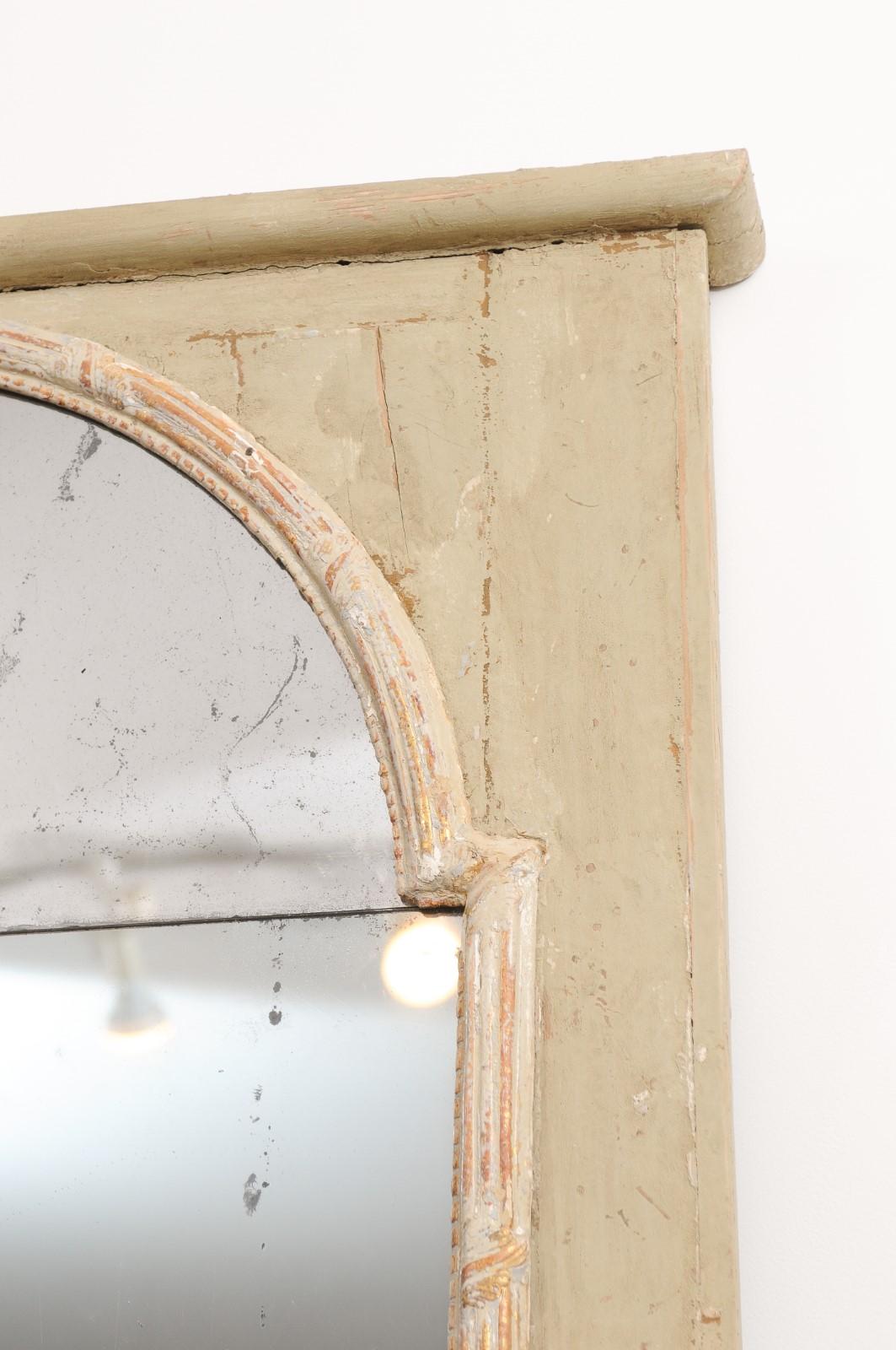 A French Régence period painted wood grand mirror from the early 18th century with broken arch motif. Created in France during the Régence that saw the transition of power between King Louis XIV and his great-grandson, King Louis XV, this mirror